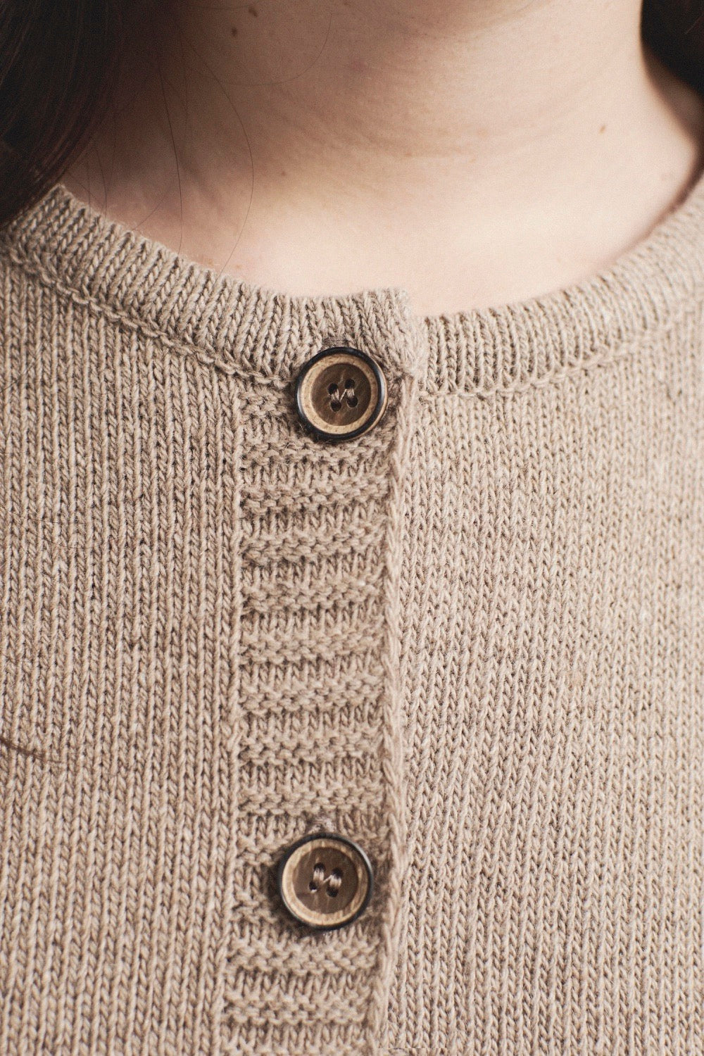 Detalle del tejido de punto beige o marrón claro del cardigan IAIOS con botones frontales, elaborado con hilo reciclado en talleres de Catalunya (España).
