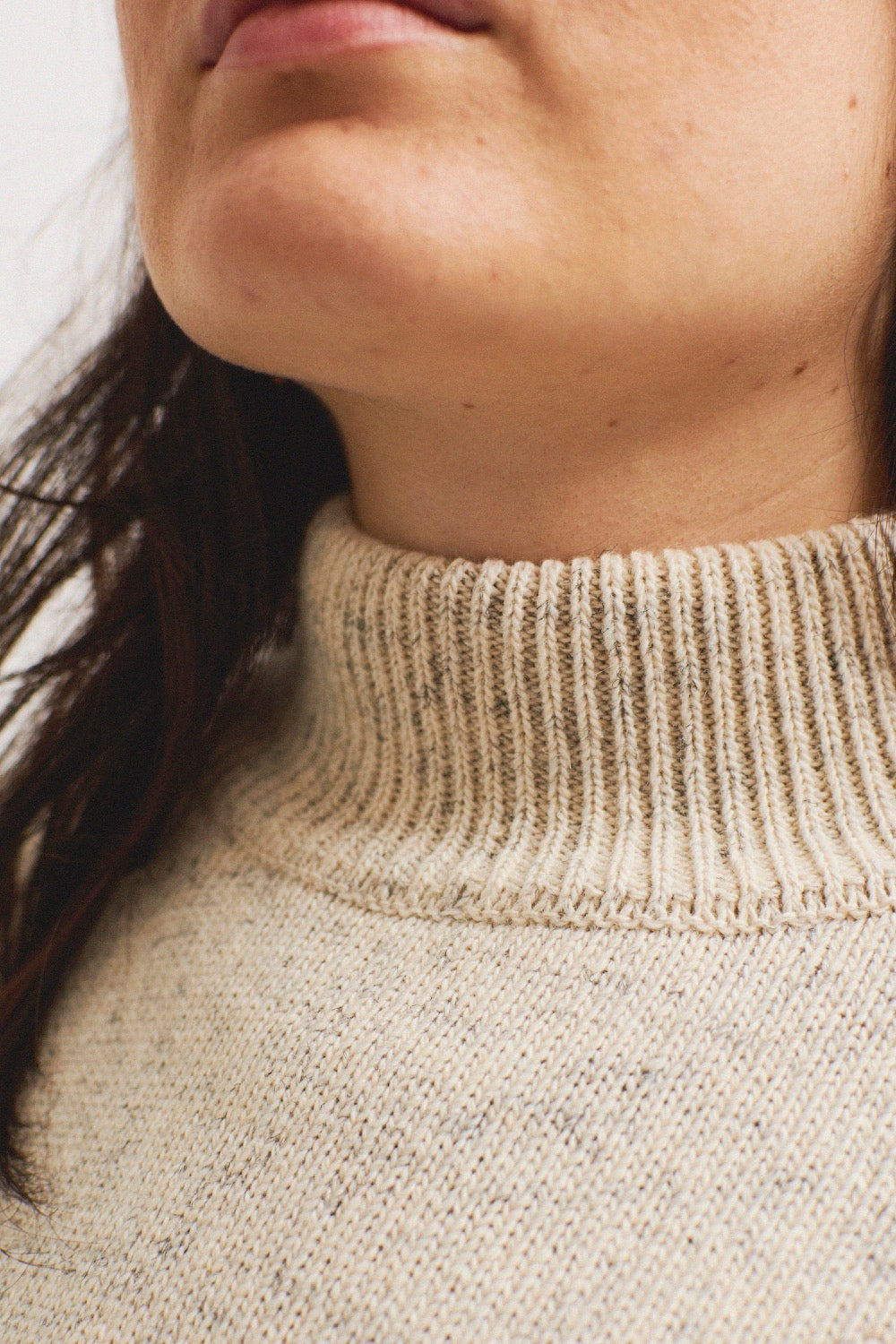 Detalle del tejido blanco jaspeado del jersey unisex IAIOS con cuello alto, elaborado con hilo reciclado en talleres de Catalunya (España).