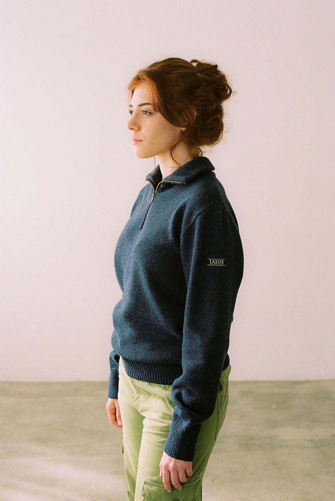 La modelo lleva el jersey IAIOS unisex azul marino con media cremallera, moda sostenible elaborada en talleres de Catalunya (España) con hilo reciclado.