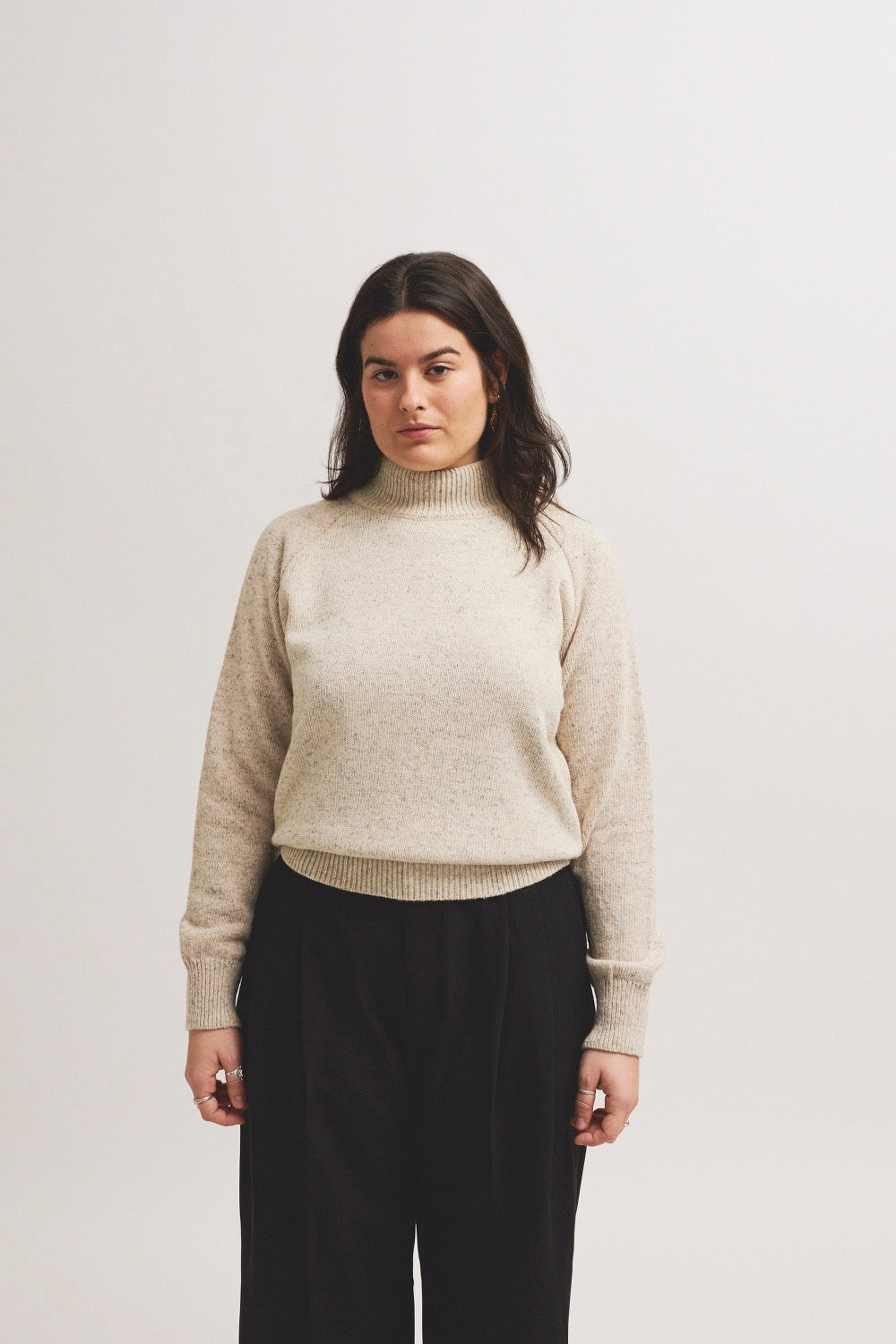 Modelo con jersey unisex IAIOS blanco jaspeado con cuello alto, ajuste cómodo y estilo minimalista, hecho en Catalunya (España) con hilo reciclado.