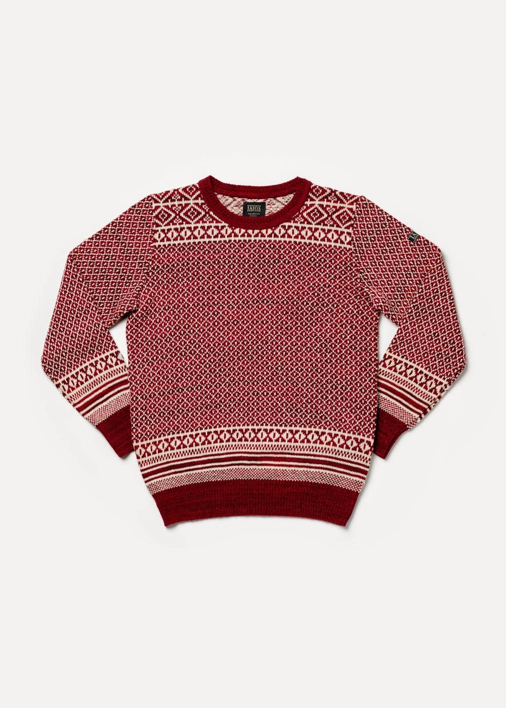 El modelo lleva el jersey unisex IAIOS rojo y blanco con diseño jacquard navideño tipo nórdico, moda sostenible hecha en Catalunya (España) con hilo reciclado, ideal para invierno.