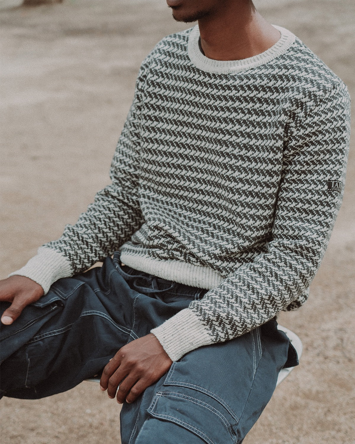 El modelo lleva el jersey unisex IAIOS de punto espiga en blanco y negro, con puños, cuello y cintura en color crema, hecho en Catalunya (España) con hilo reciclado.