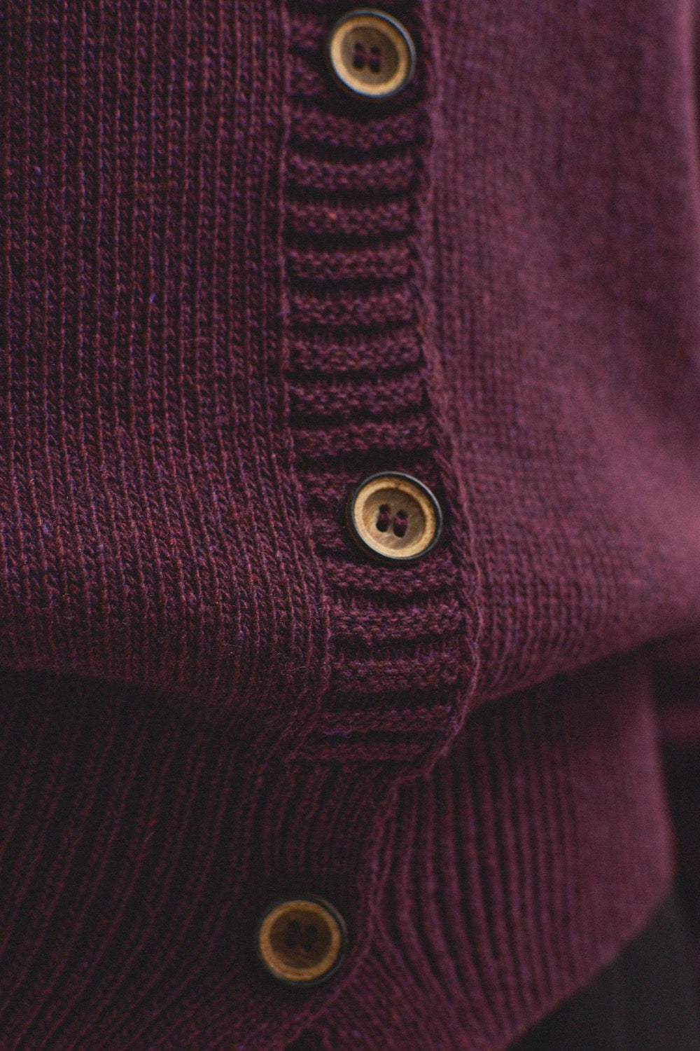 Detalle del tejido de punto color vino o berenjena del jersey IAIOS con botones frontales, elaborado con hilo reciclado en talleres de Catalunya (España).