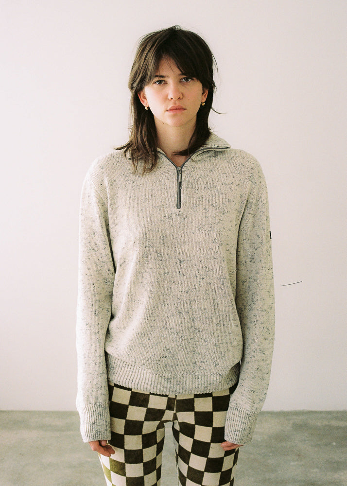 La modelo lleva el jersey IAIOS unisex blanco con media cremallera, moda sostenible elaborada en talleres de Catalunya (España) con hilo reciclado.
