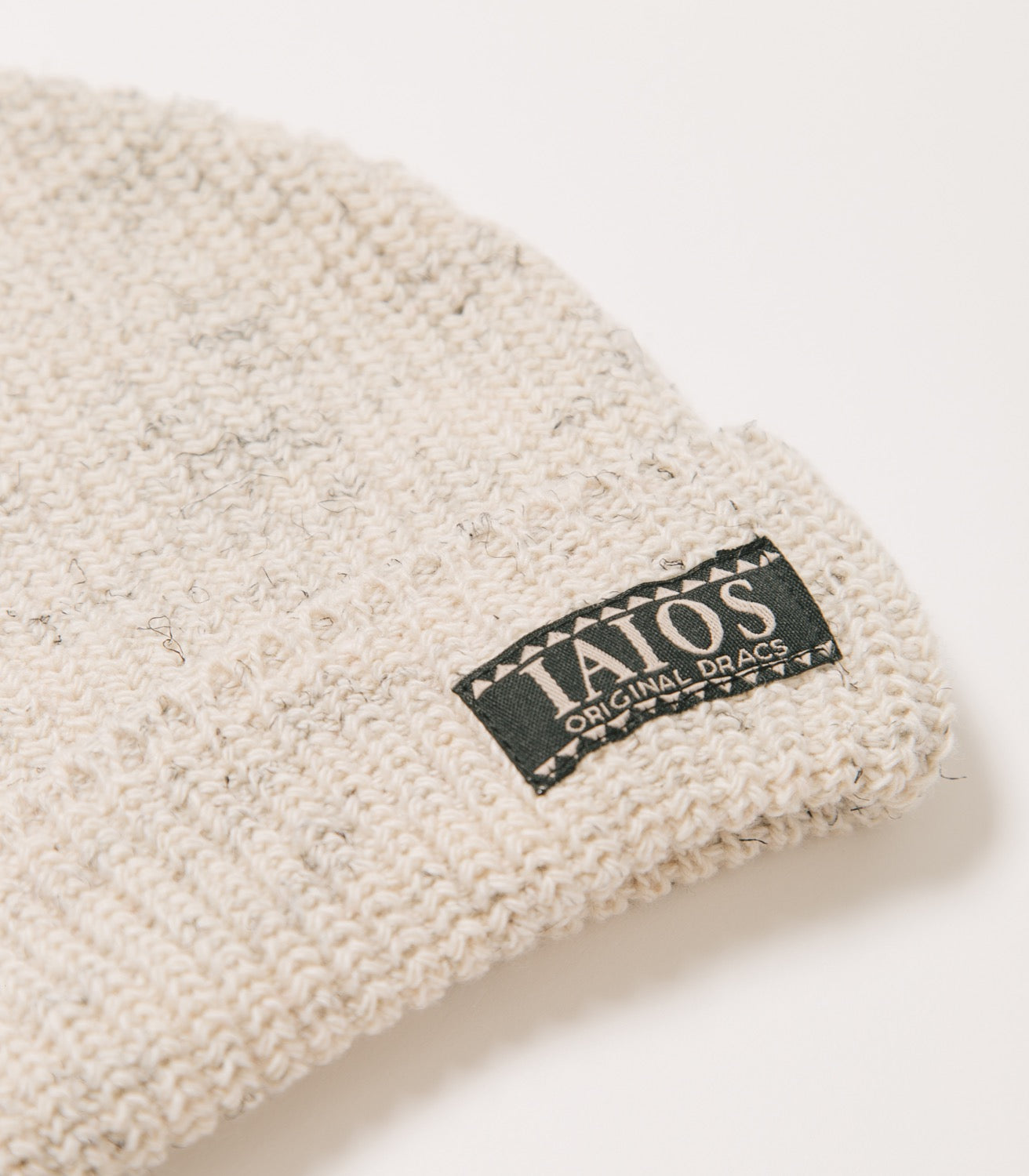 Detalle de la etiqueta IAIOS que lleva el gorro blanco