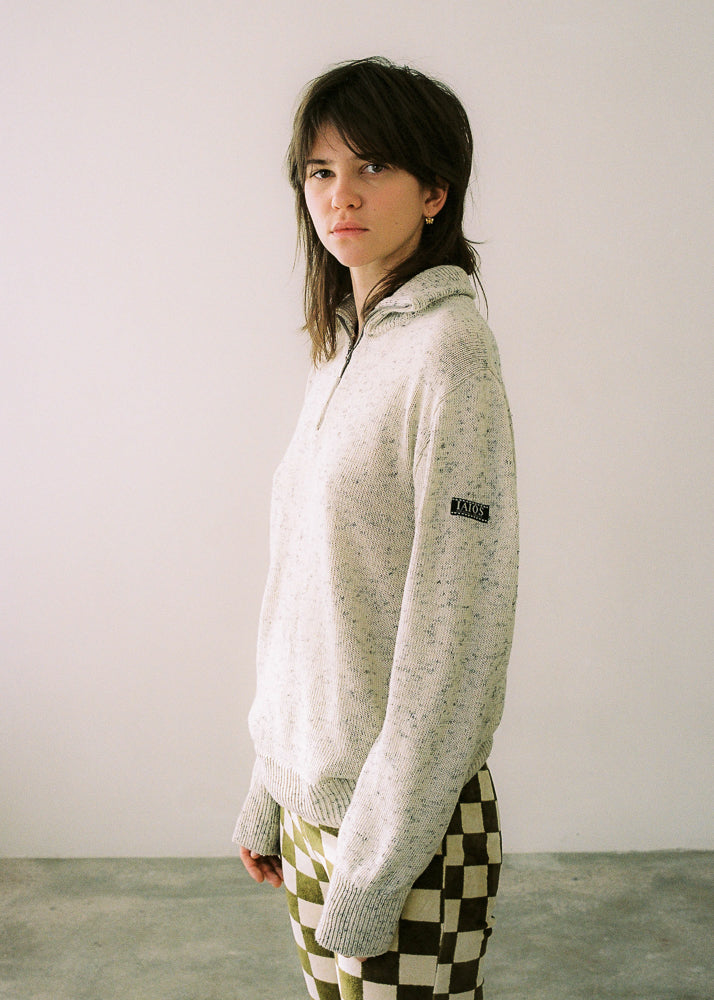 La modelo lleva el jersey unisex IAIOS blanco con media cremallera, moda sostenible hecha en Catalunya (España) con hilo reciclado, básico atemporal ideal para invierno.