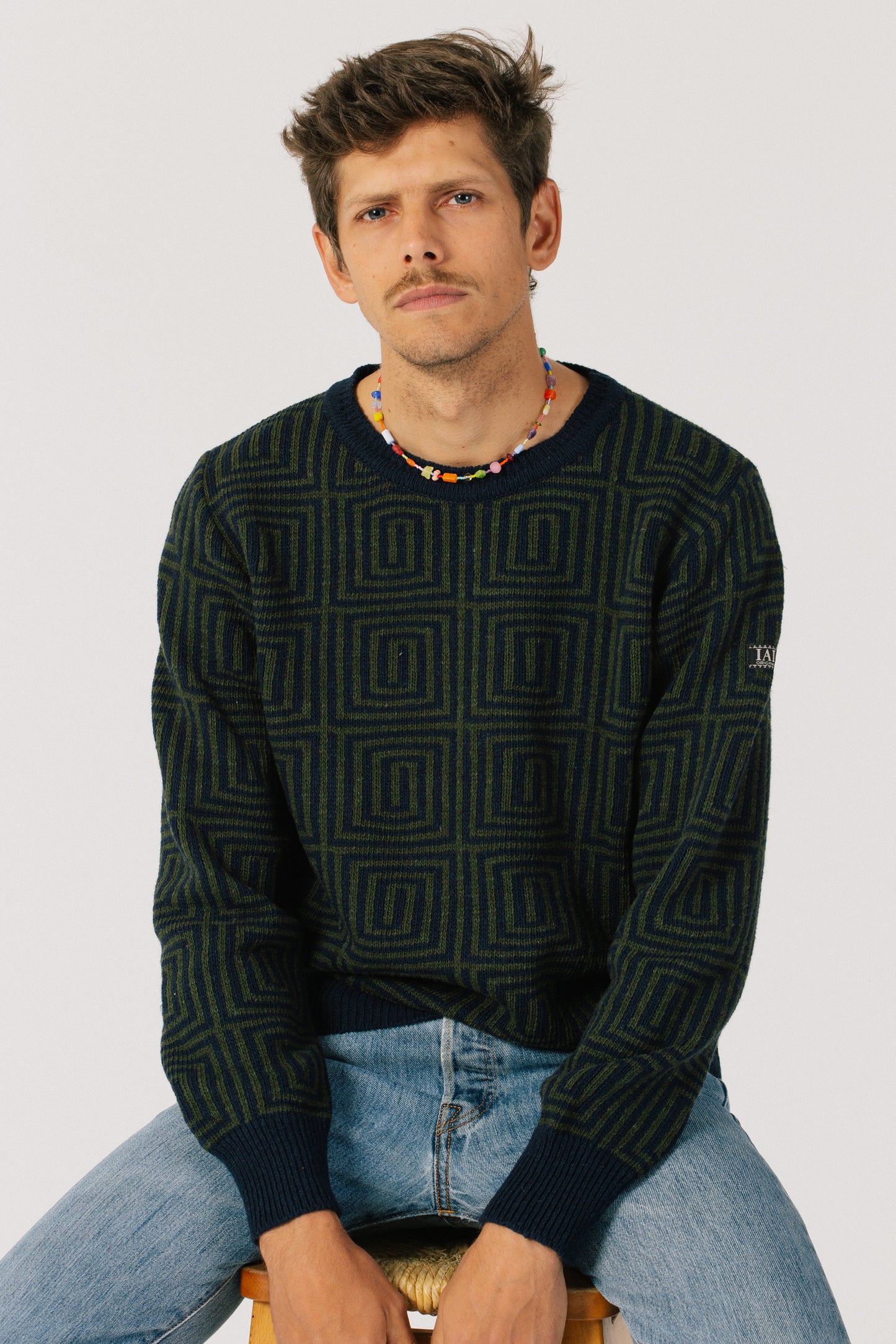 Model sitting with the sweater. The dark colors give it an elegant and discreet touch.