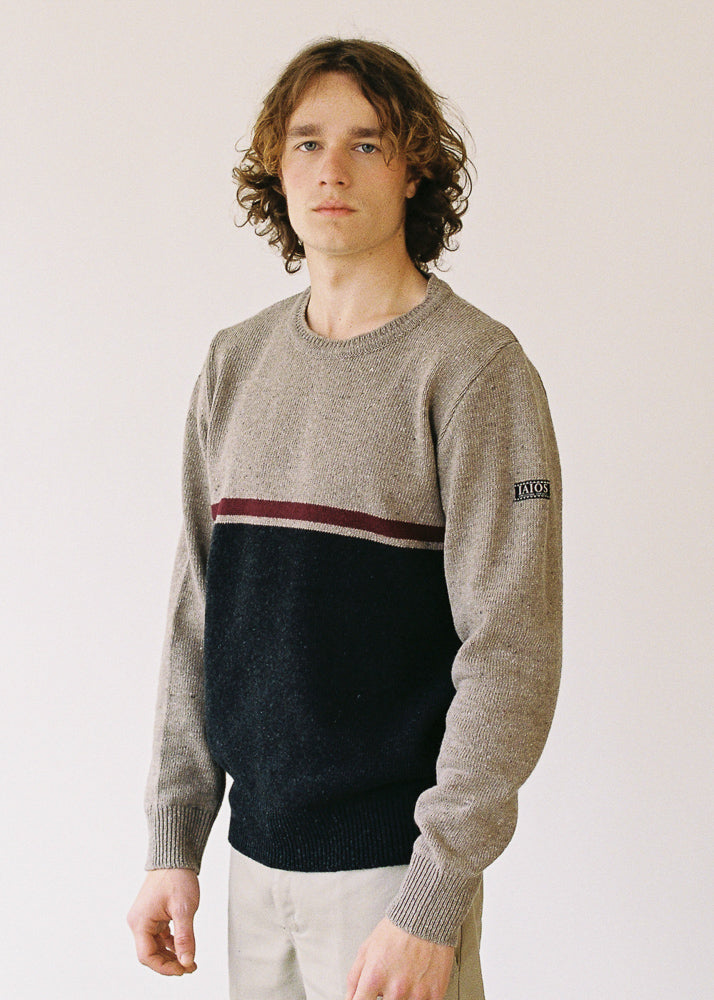 El modelo lleva el jersey IAIOS unisex negro y marrón claro con detalle granate, moda sostenible elaborada en talleres de Catalunya (España) con hilo reciclado.