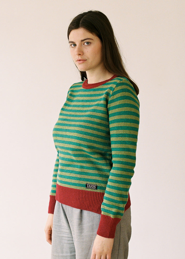 La modelo lleva el jersey unisex IAIOS de rayas verde y rojo, moda sostenible hecha en Catalunya (España) con hilo reciclado, ideal para invierno.