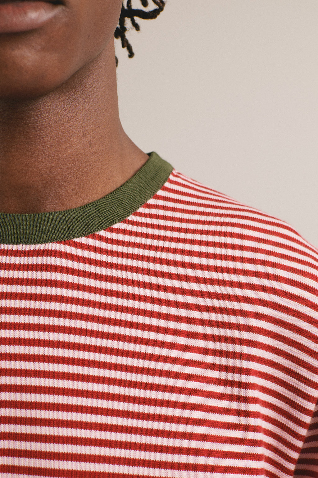 Detalle de la camiseta de punto con estampado de rayas rojas y rosas. El cuello es de color verde oscuro.