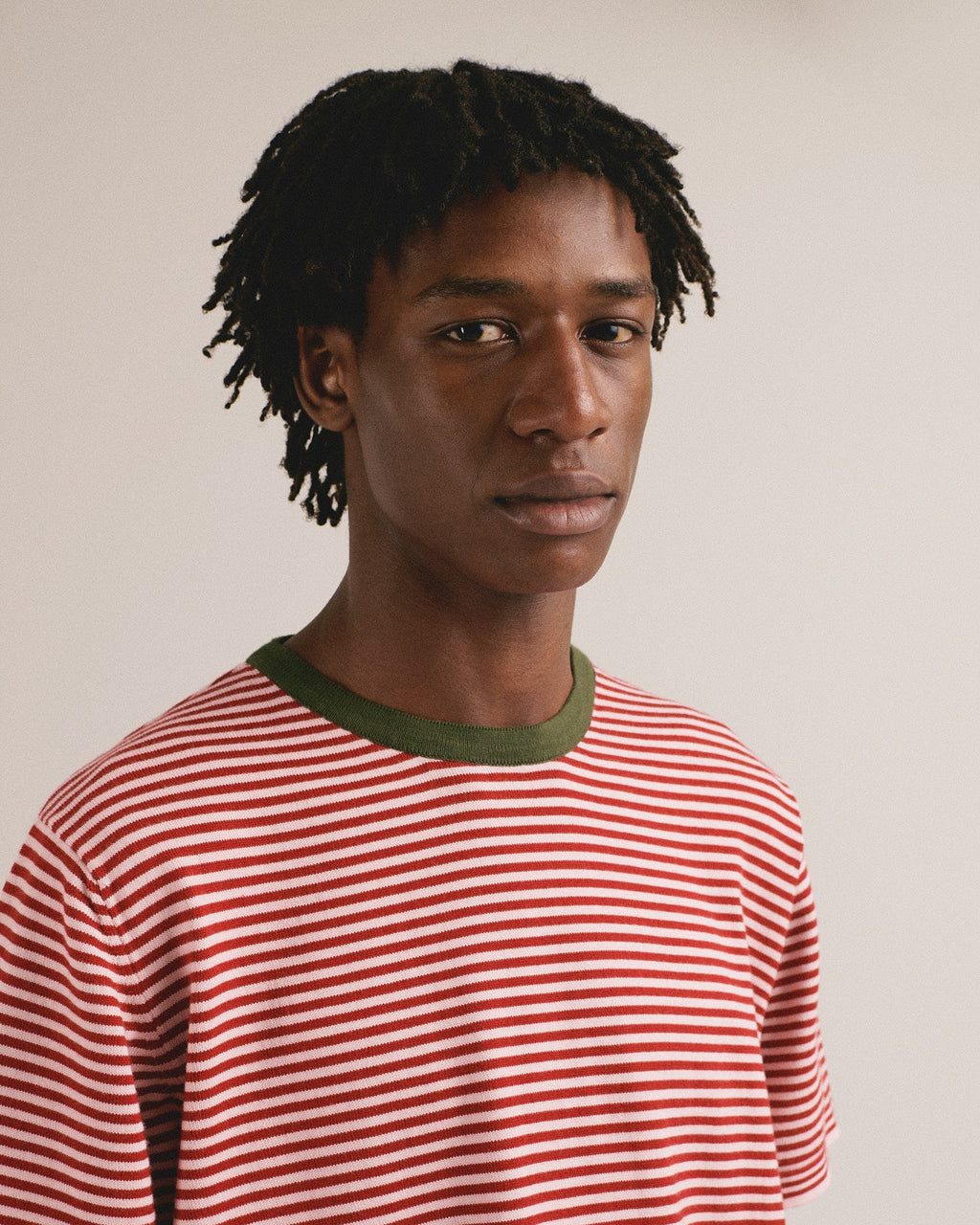 Camiseta de punto con estampado de rayas rojas y rosas. El cuello es de color verde oscuro.