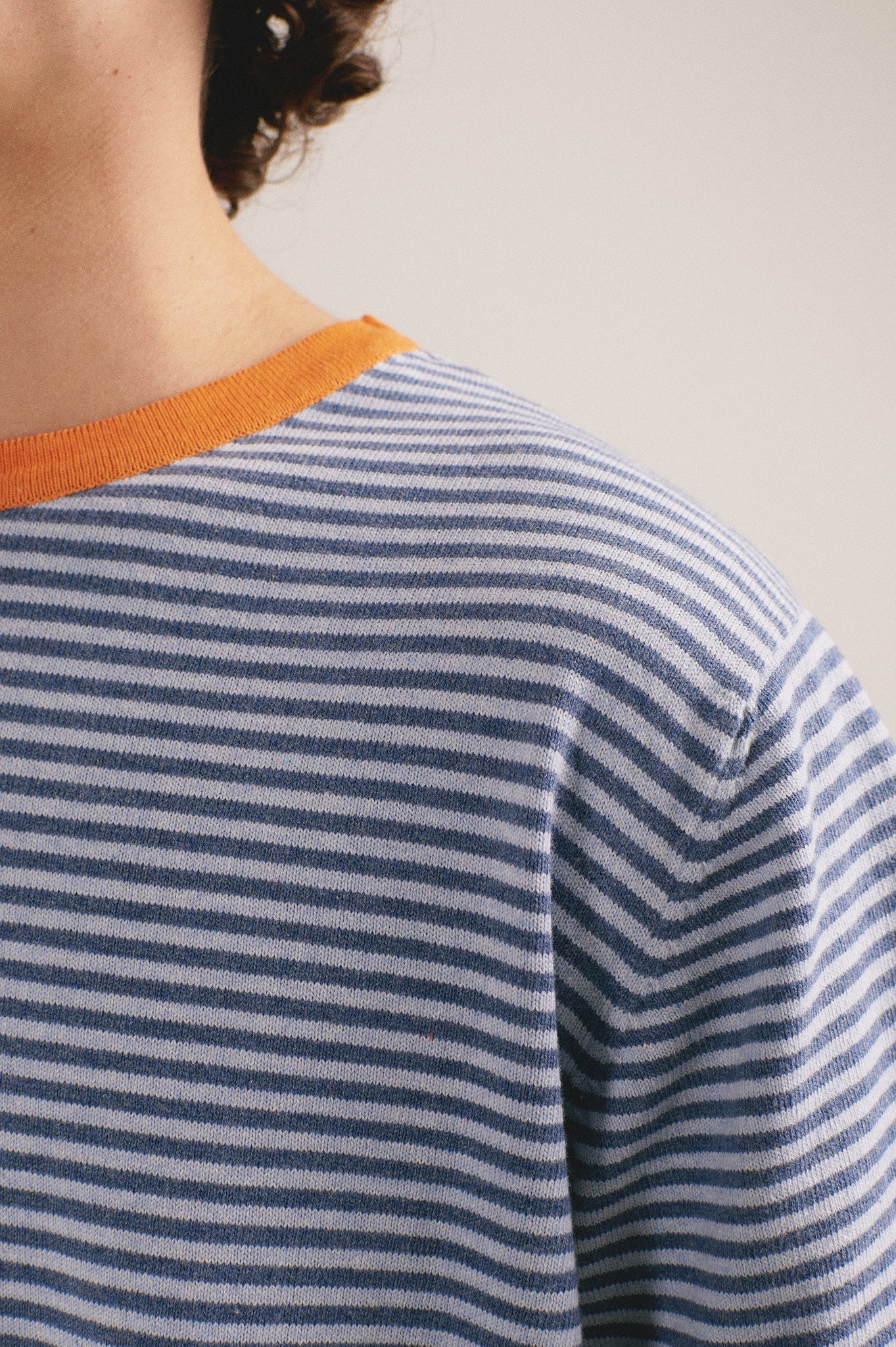 Detalel de la camiseta manga corta de punto de rayas azules con cuello naranja