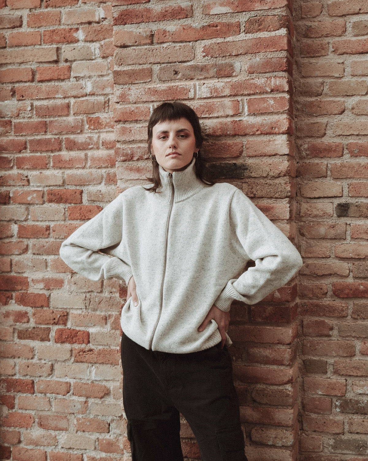 White jersey with a bit of twit with a zipper all the way down and a high neck. It is worn by a girl as it is a unisex style.
