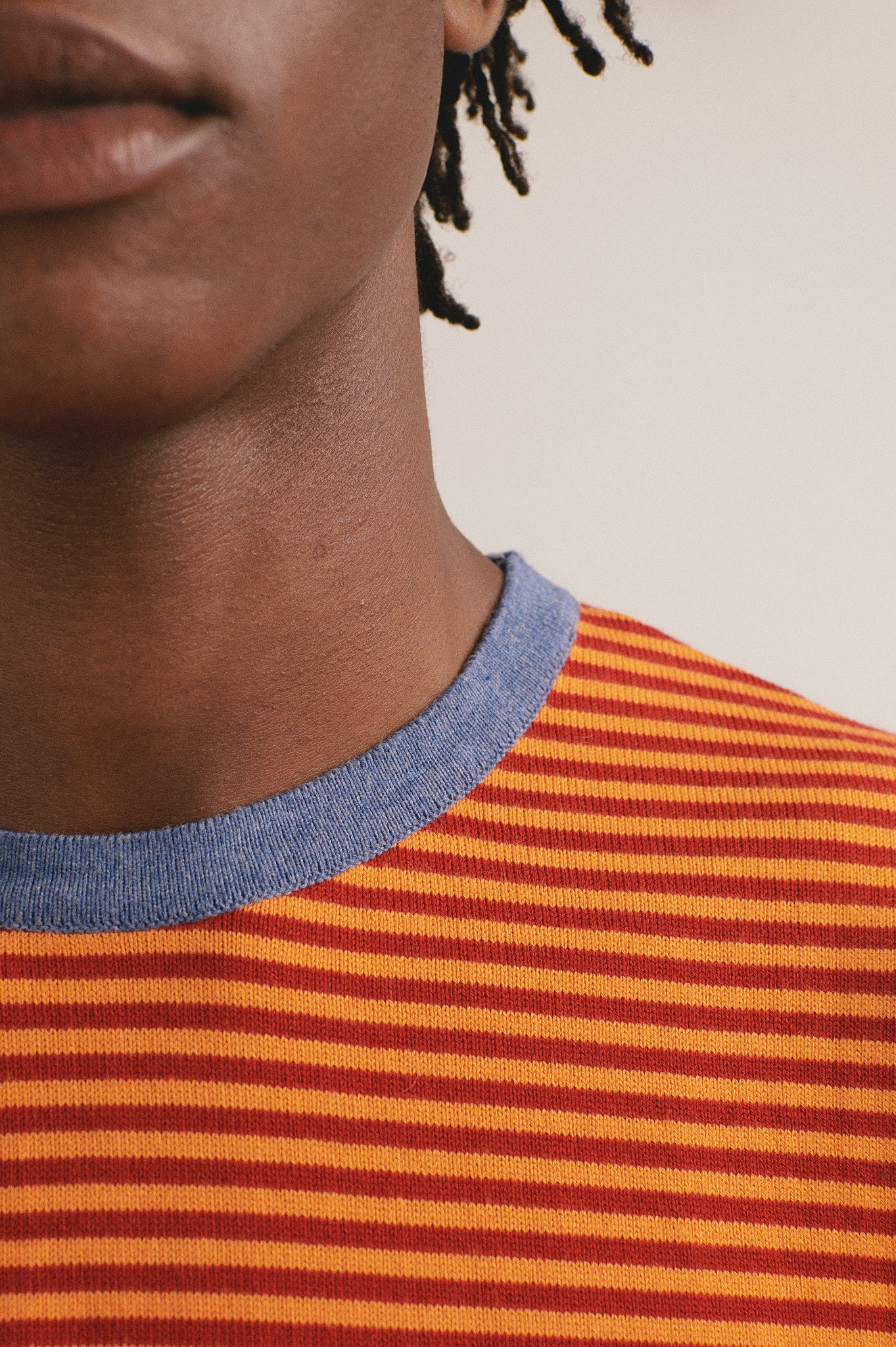 Camiseta de punto de rayas con tonos naranja y cuello azul. Algodón orgánico y fabricación local.