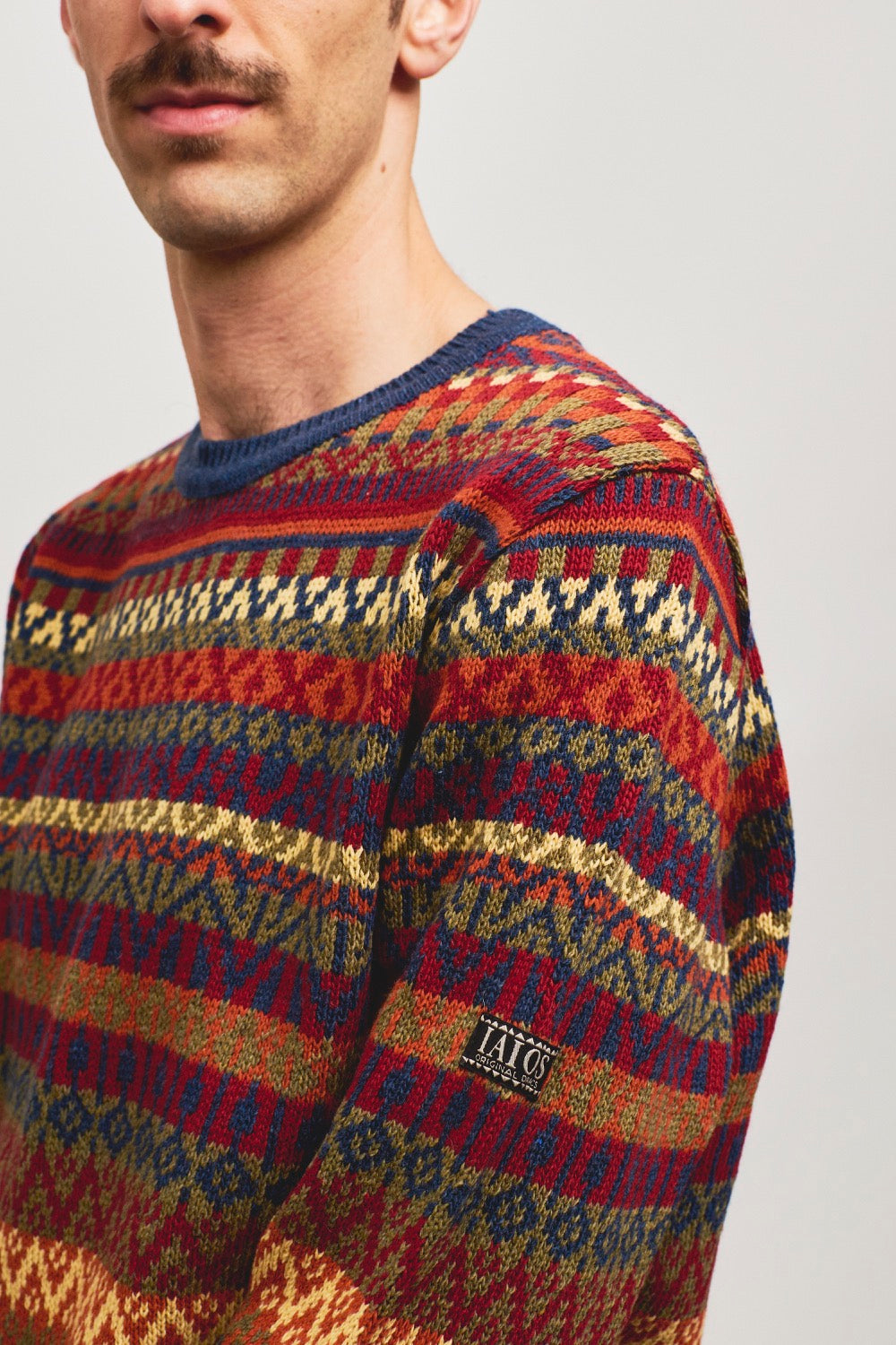 Jersey de punto de hombre o unisex de tonos rojos, naranjas y azules. Es un jacquard de 5 colores por lo que se consigue un resultado de jersey navideño.