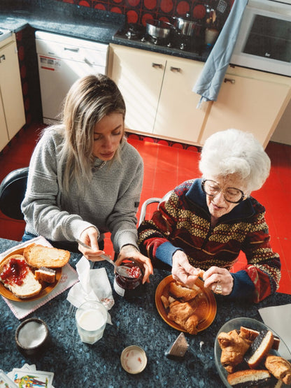 Una nieta y su abuela desayunan en la cocina. Llevan jesreys de la marca IAIOS hechos con materiales reciclados.