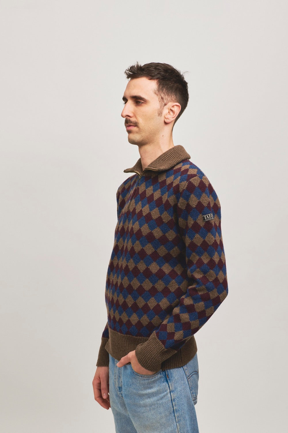 Jersey de punto con cremallera en el cuello. Es un diseño de rombos azul, granate y barron.