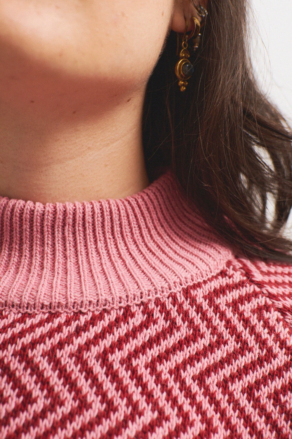 Detalle del tejido en zigzag burdeos sobre fondo rosa del jersey de mujer IAIOS, elaborado con hilo reciclado en talleres de Catalunya (España).