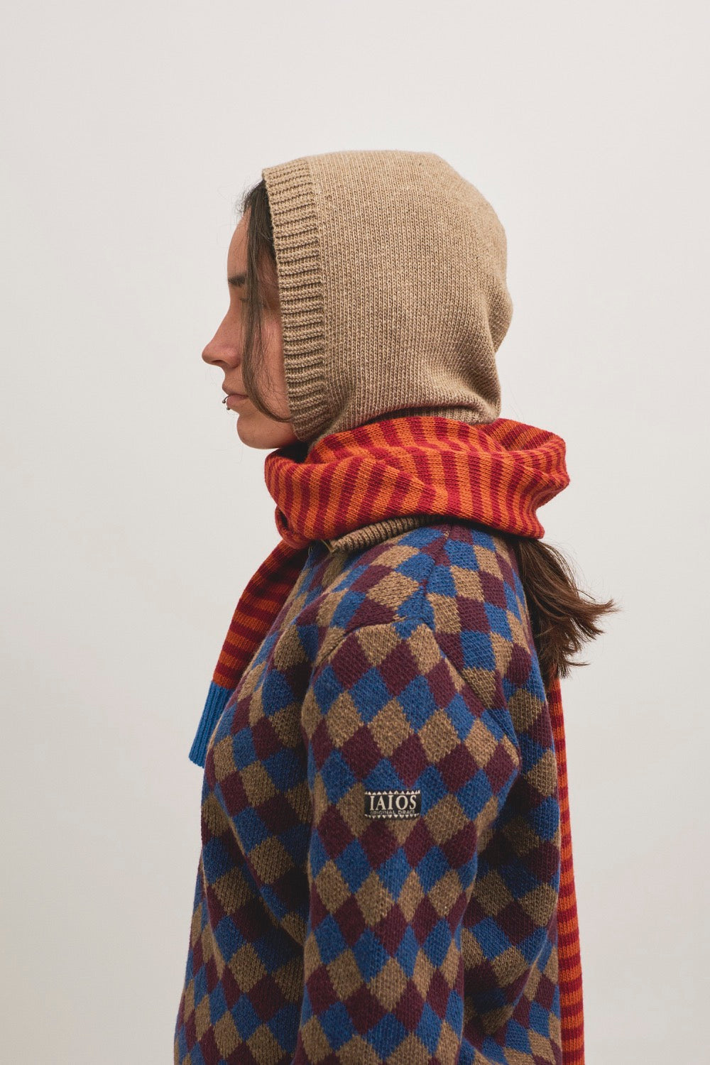 Modelo con el jersey de rombos y una bufanda de rayas y una balaclava beige.