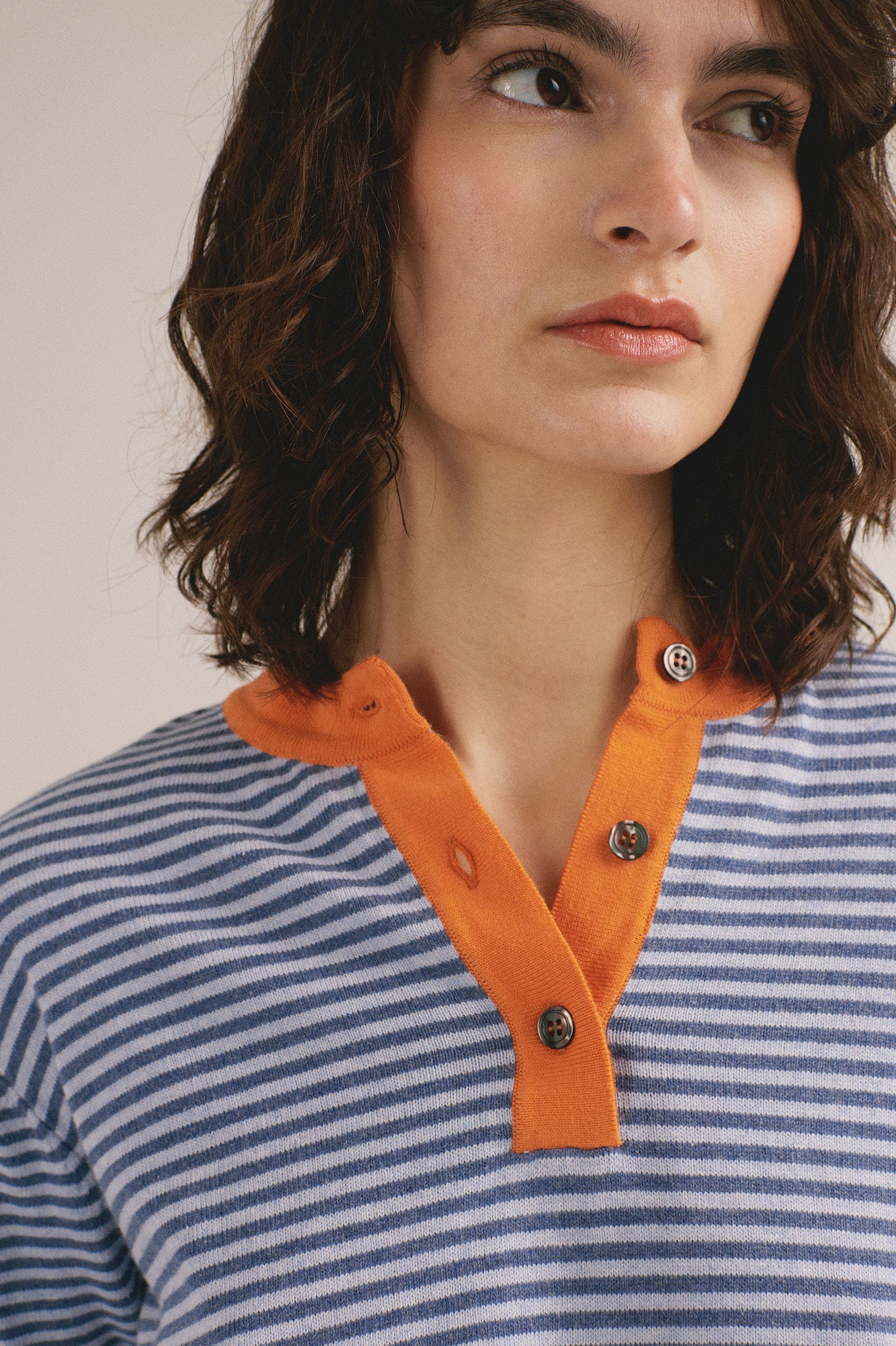 Polo de rayas azul y naranja para mujer con cuello de botones. 