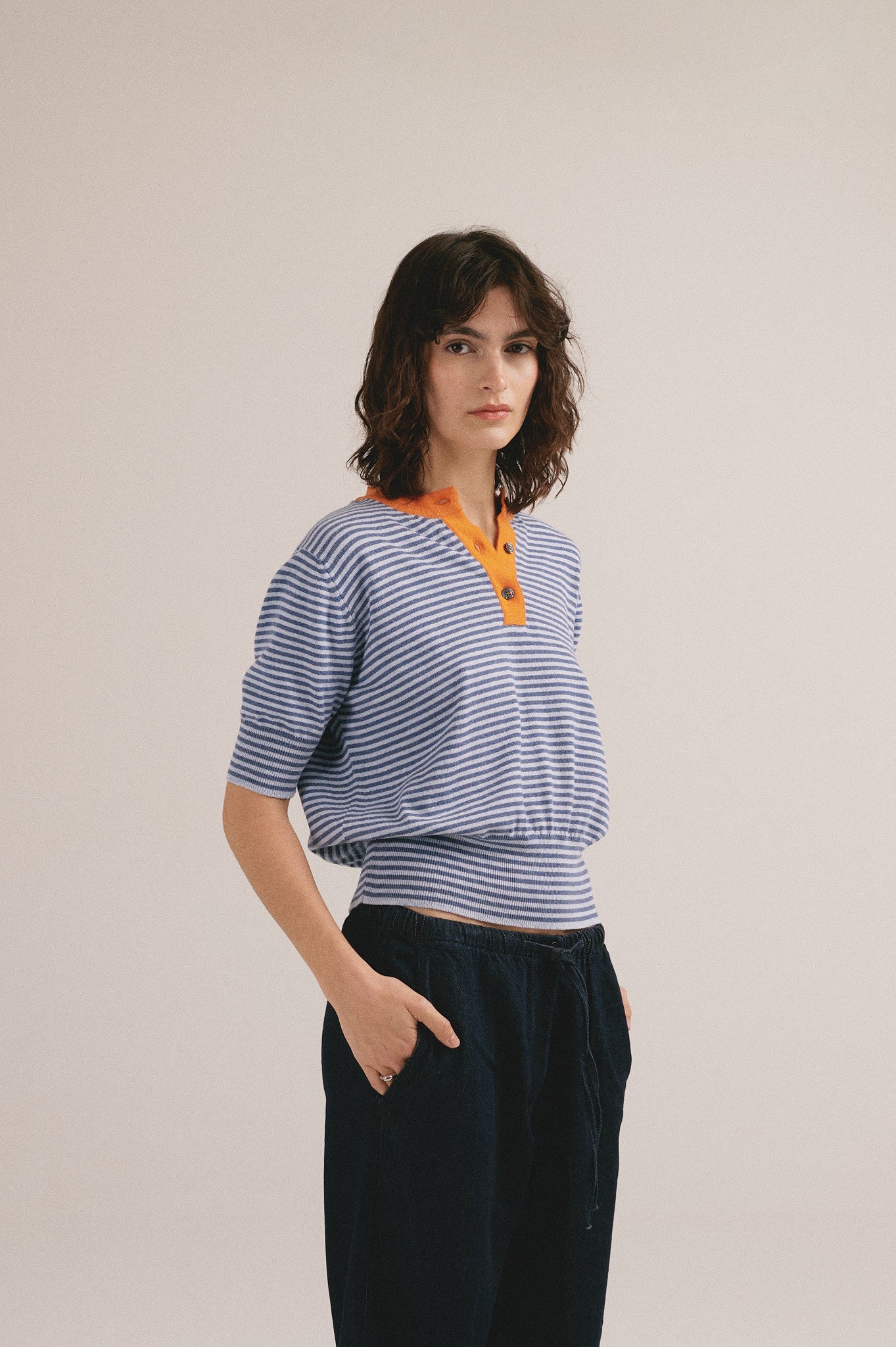 Polo de rayas azul y naranja para mujer con cuello de botones. 