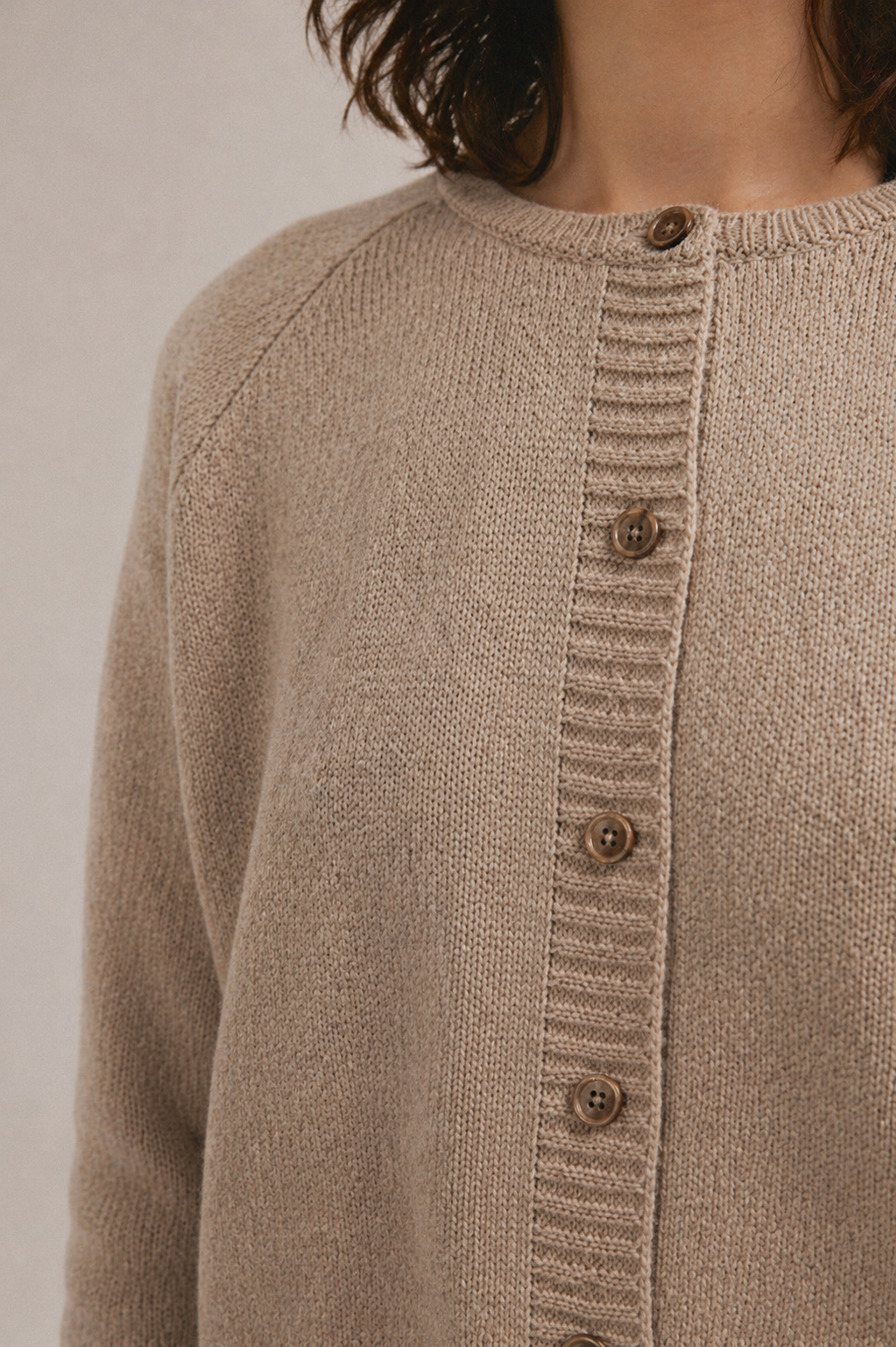 Cárdigan de punto para mujer en color beige con cierre de botones, combinado con top azul.
