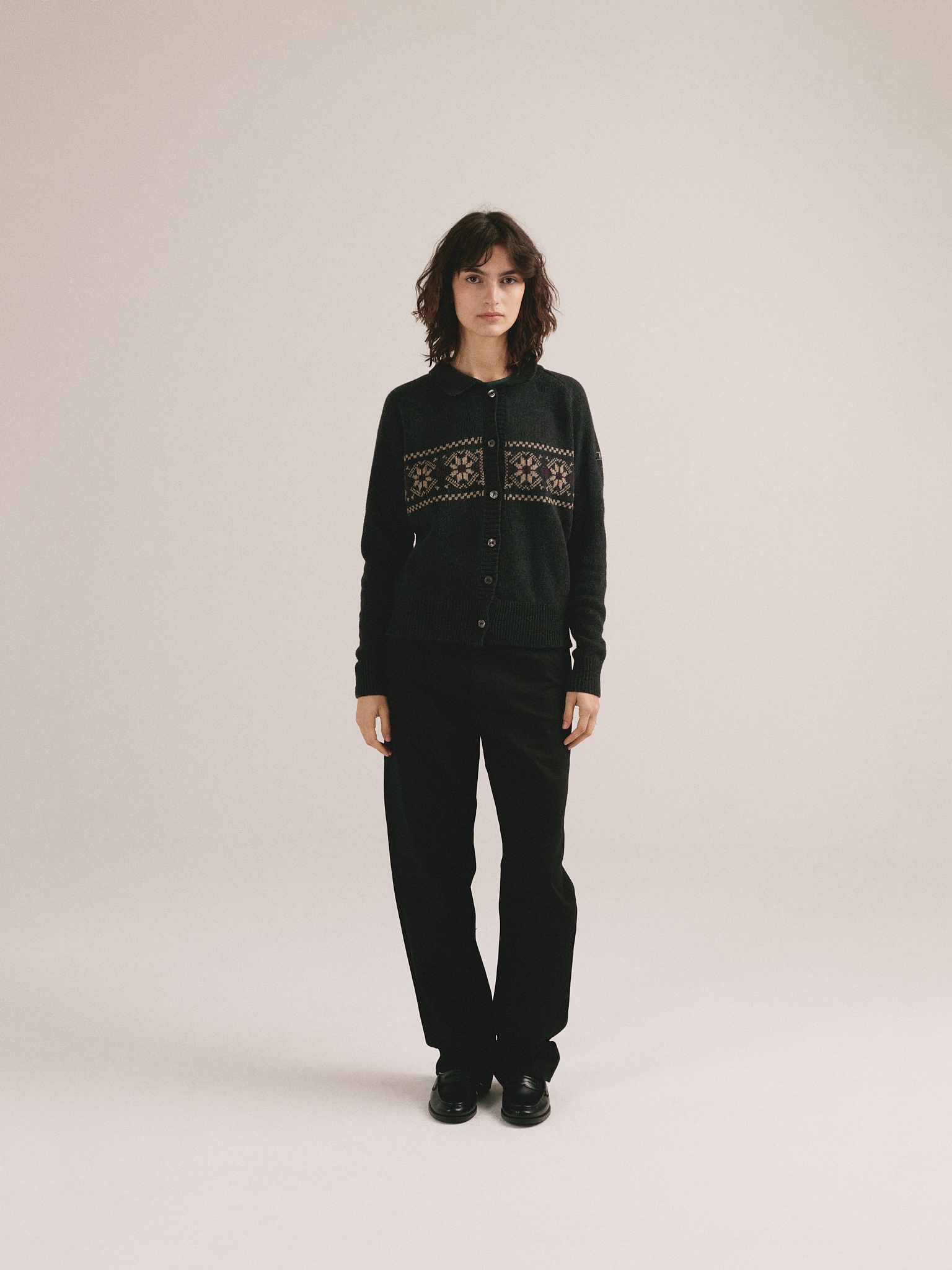 Modelo femenina con chaqueta de punto negra con diseño jacquard y cierre frontal de botones de IAIOS.