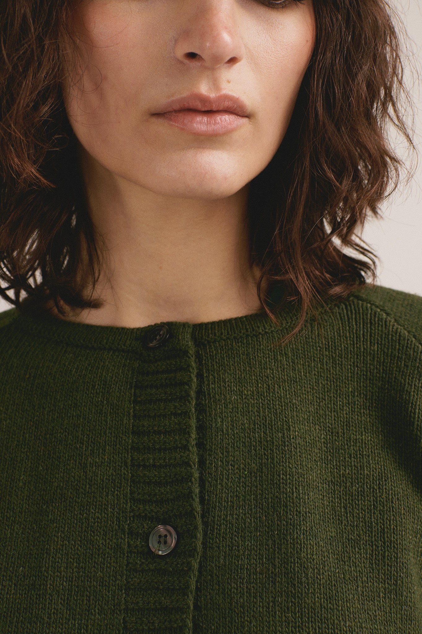 Modelo femenina con chaqueta de punto verde oliva de manga larga con botones frontales de IAIOS.