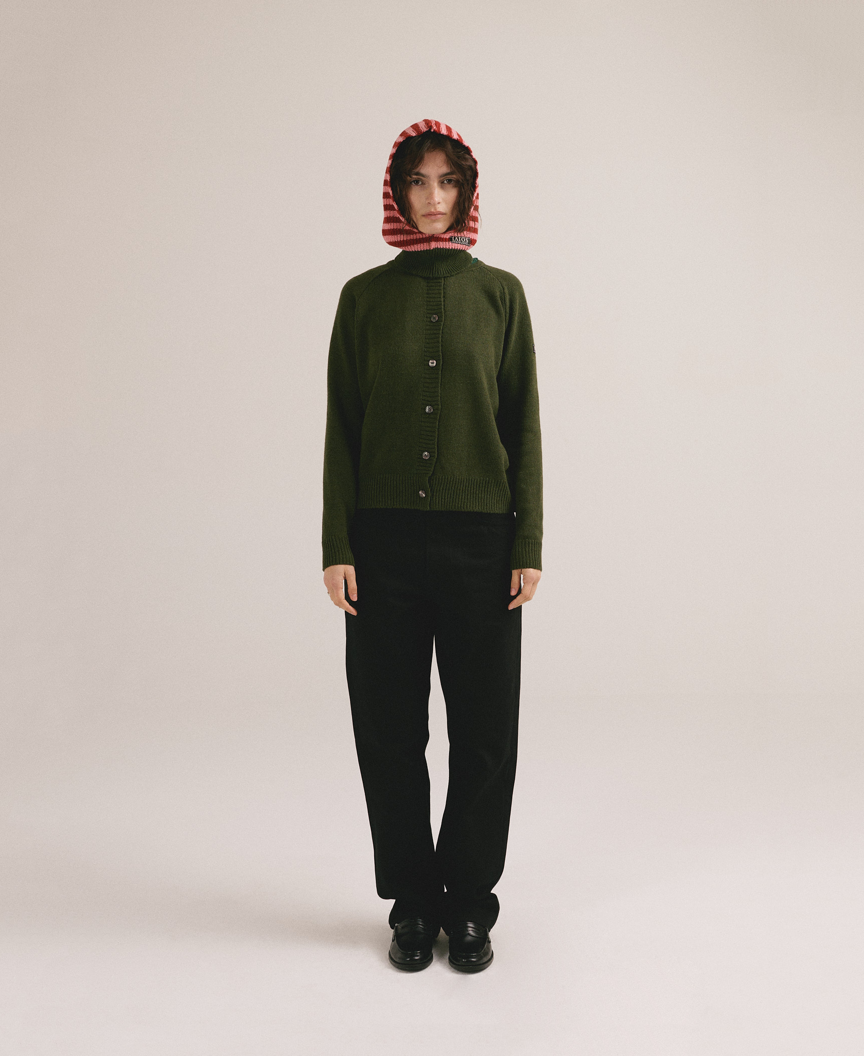 Mujer joven vistiendo cárdigan verde de punto con cierre de botones y estilo casual minimalista.
