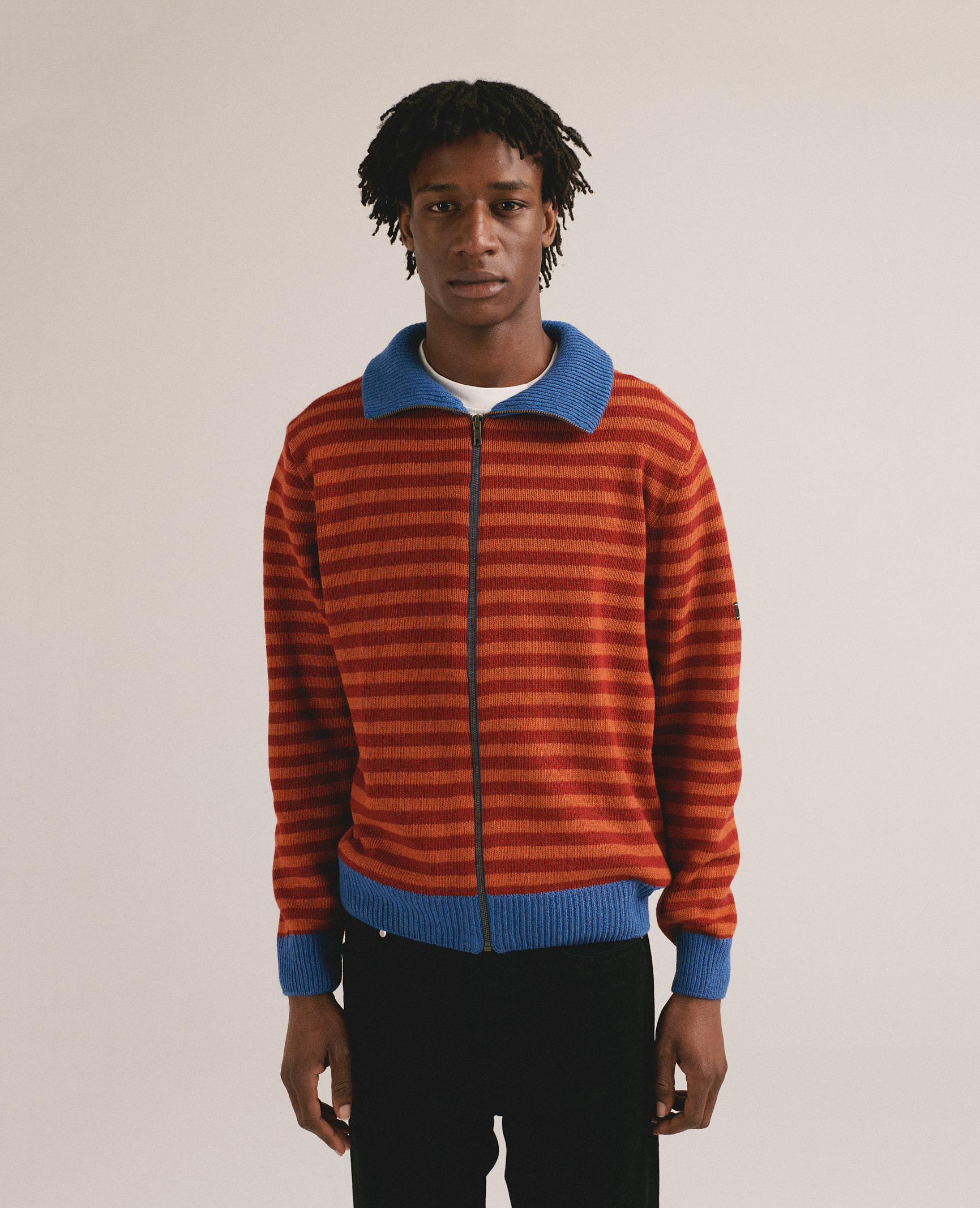 Hombre con chaqueta de punto a rayas rojas y azules con cremallera