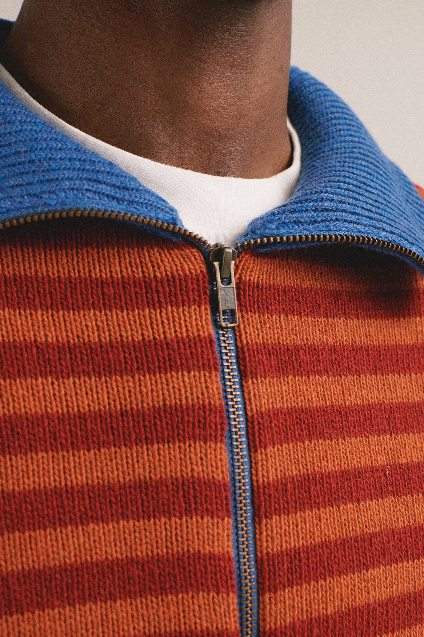Hombre vistiendo chaqueta de punto rayada con cuello azul y cremallera