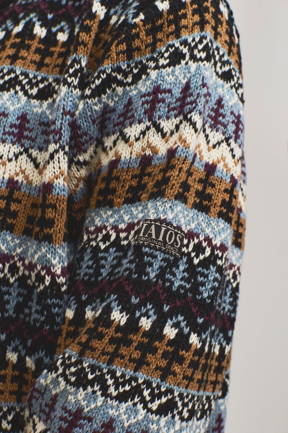 Detalle del tejido jacquard tipo Gansey del jersey nórdico en azul y beige, puños y cuello negros, elaborado con hilo reciclado en talleres de Catalunya
