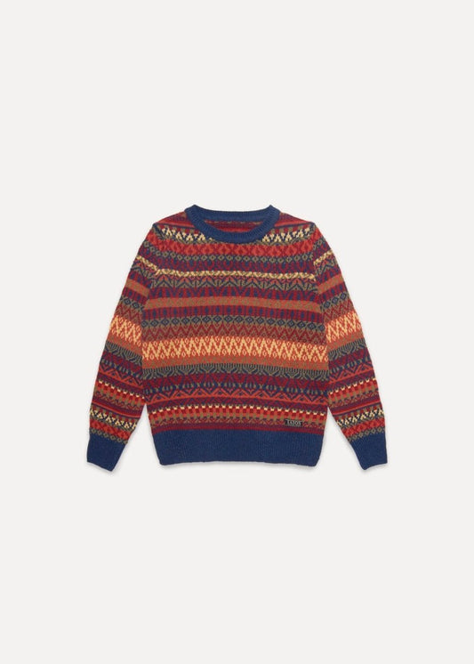 El modelo lleva el jersey unisex IAIOS colorido de inspiración navideña en tonos rojos, naranjas y azules, moda sostenible hecha en Catalunya (España) con hilo reciclado.
