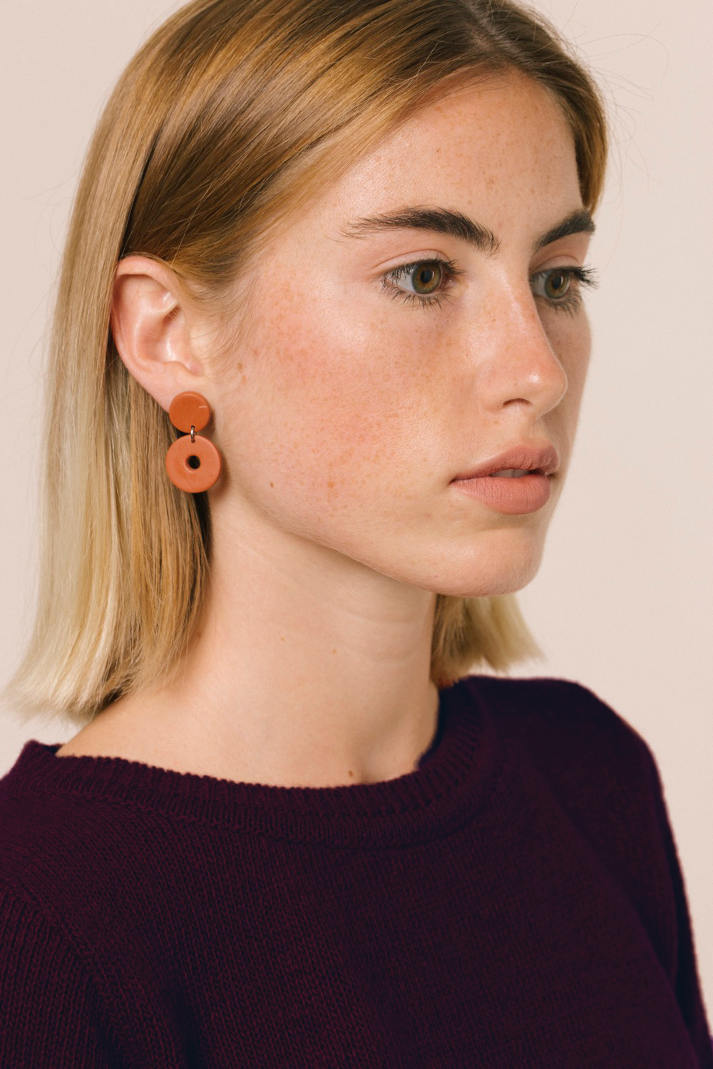 La modelo lleva el jersey de mujer IAIOS granate liso, patrón femenino básico y recto, moda sostenible hecha en Catalunya (España) con hilo reciclado, ideal para invierno.