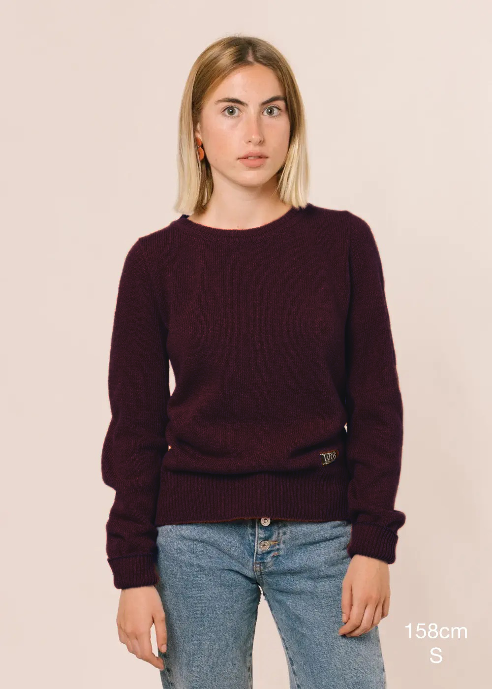 La modelo lleva el jersey IAIOS de mujer granate con aberturas laterales, moda sostenible elaborada en talleres de Catalunya (España) con hilo reciclado.