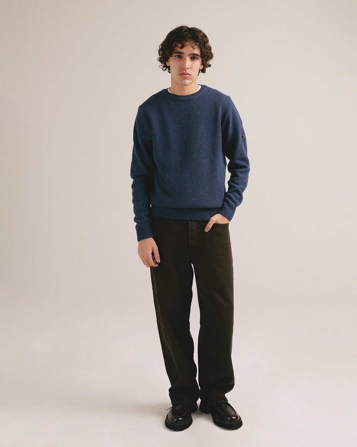 Modelo masculino con suéter de punto azul marino de manga larga con diseño básico de IAIOS.