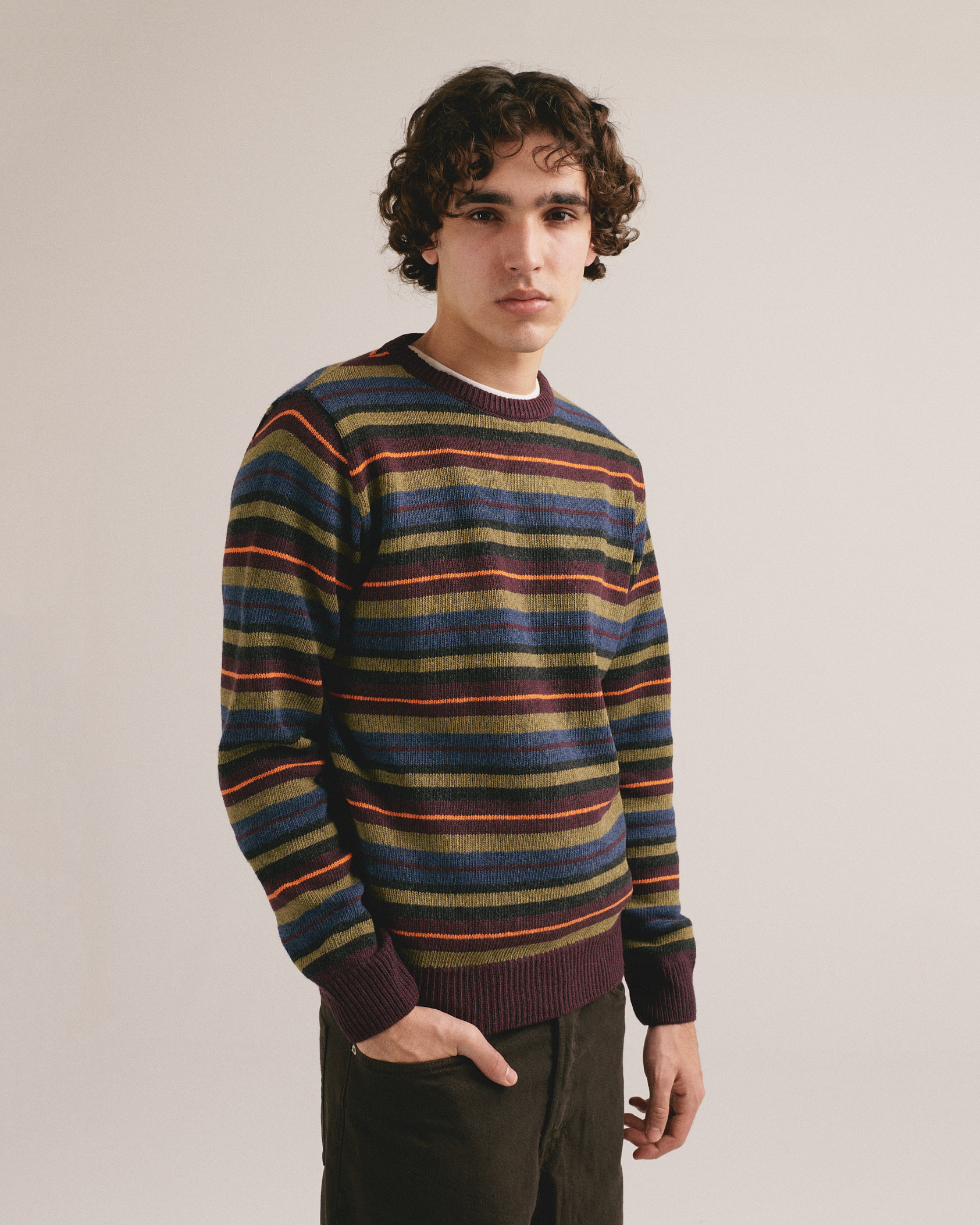 Hombre con jersey de punto a rayas multicolor en tonos azul, verde y granate