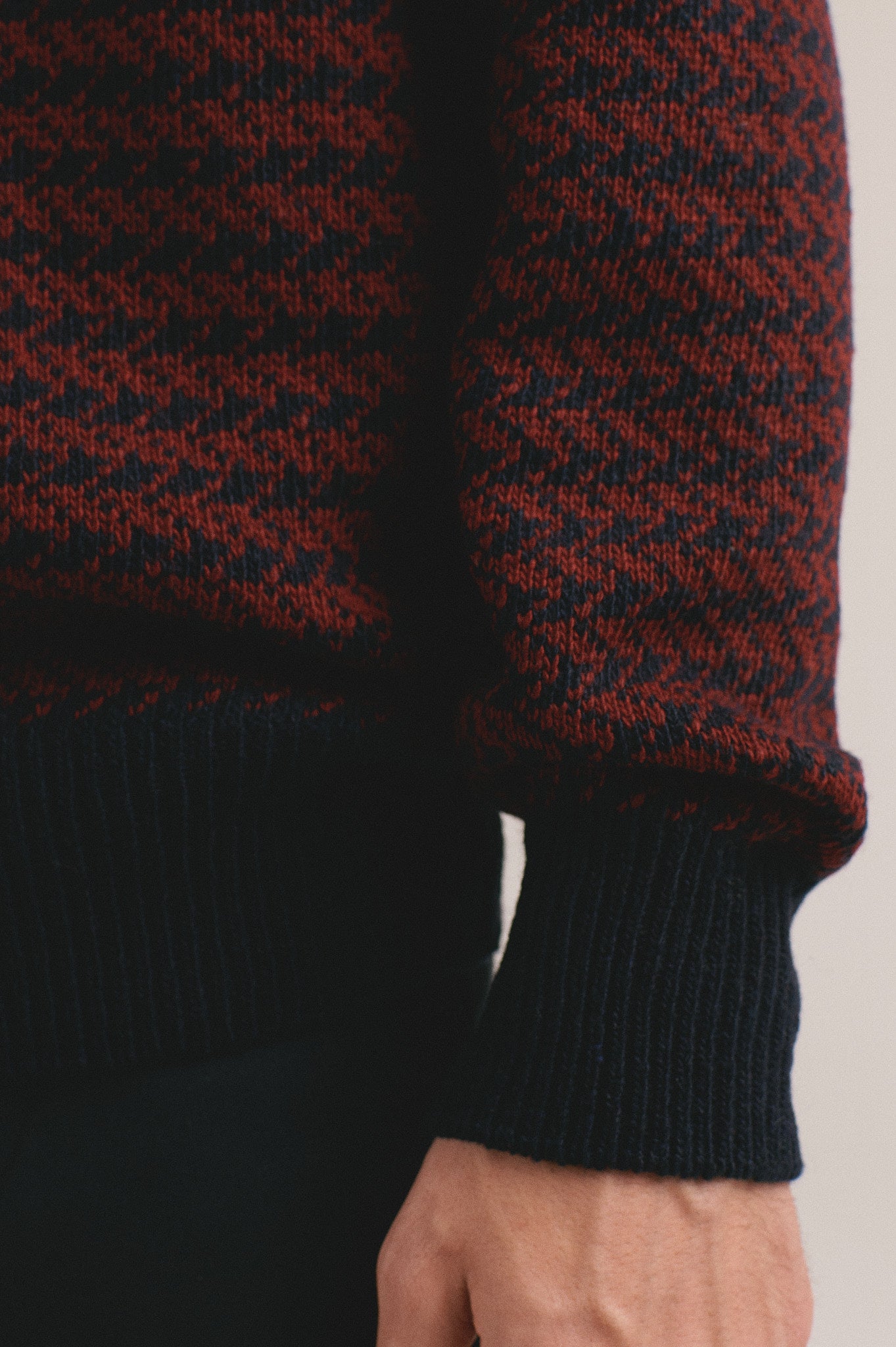 Detalle suéter bicolor rojo oscuro y negro para hombre con acabado de punto