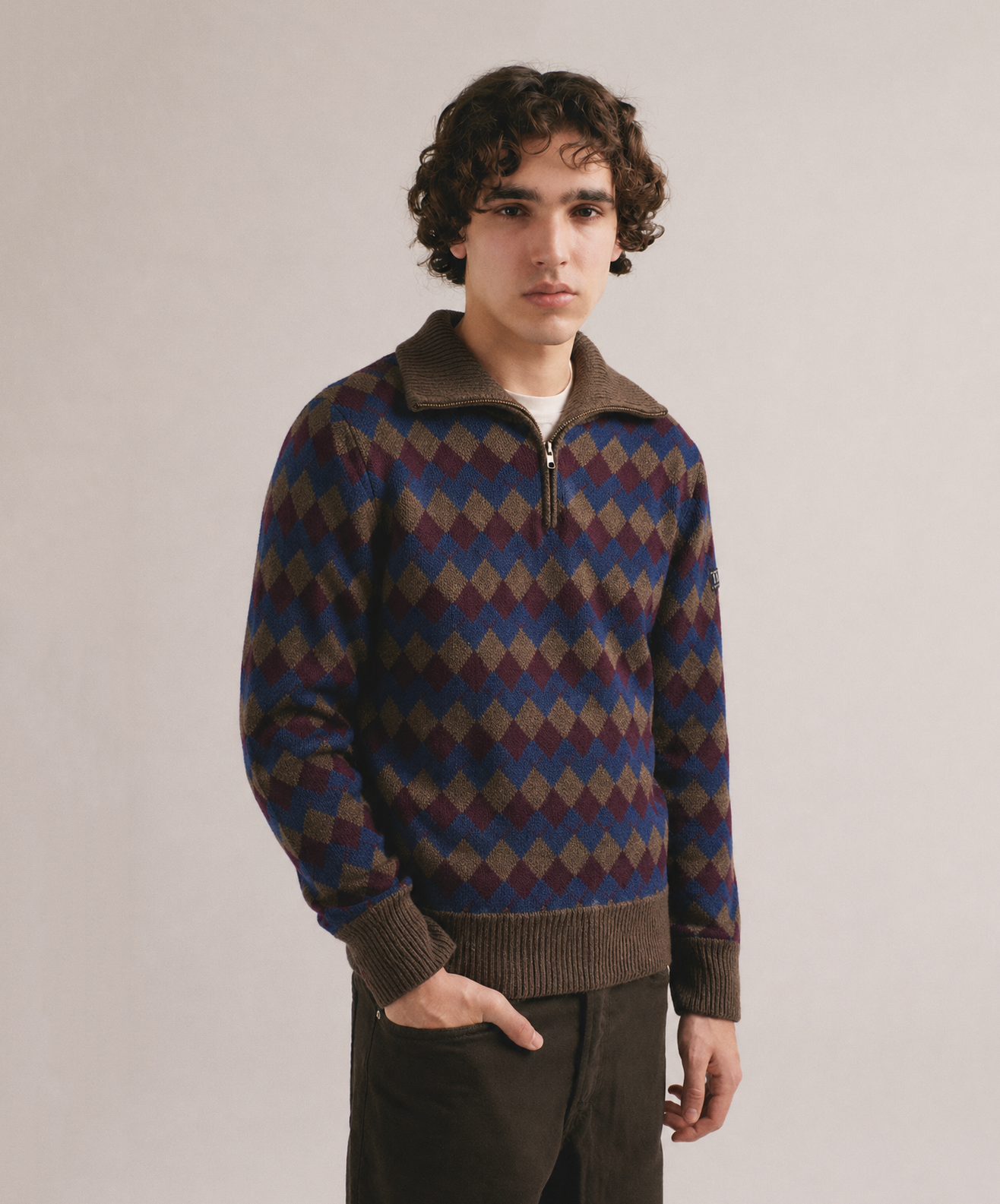 Hombre con jersey de punto con patrón de rombos multicolor y cuello con cremallera