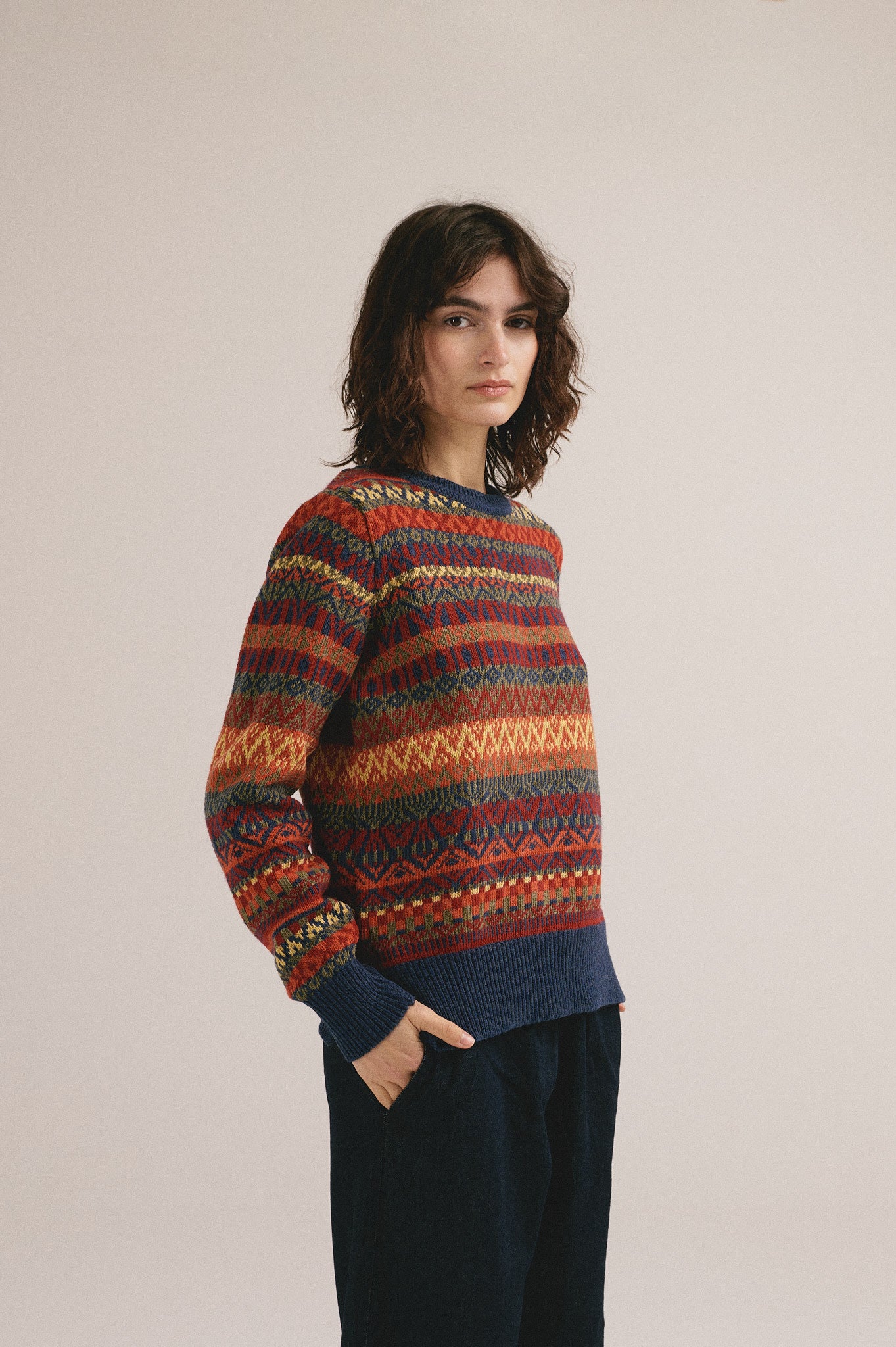 Mujer con jersey de punto multicolor con estampado geométrico de IAIOS y pantalón oscuro.