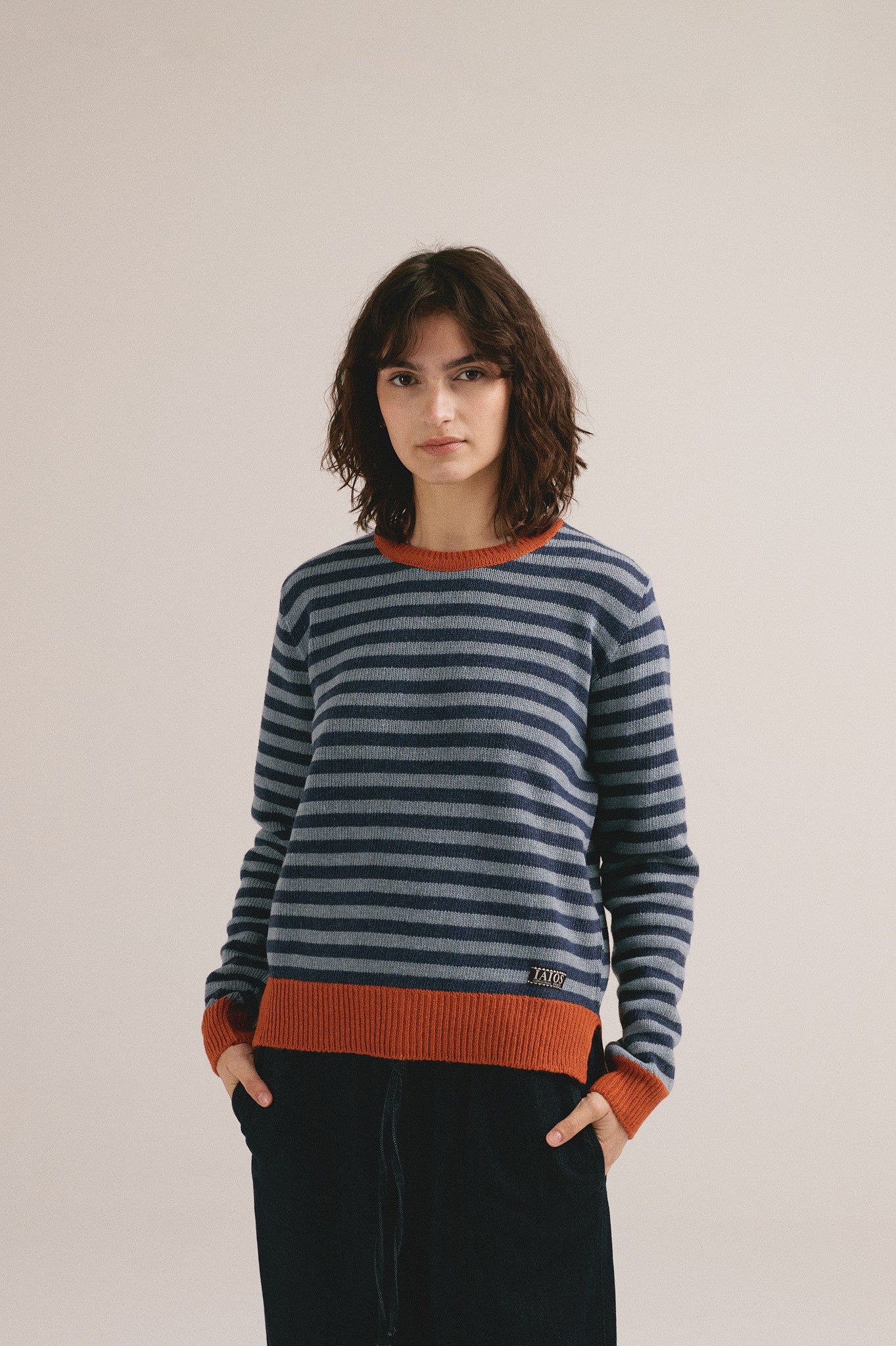 Mujer joven vistiendo jersey de punto a rayas azul y gris con estilo casual moderno.