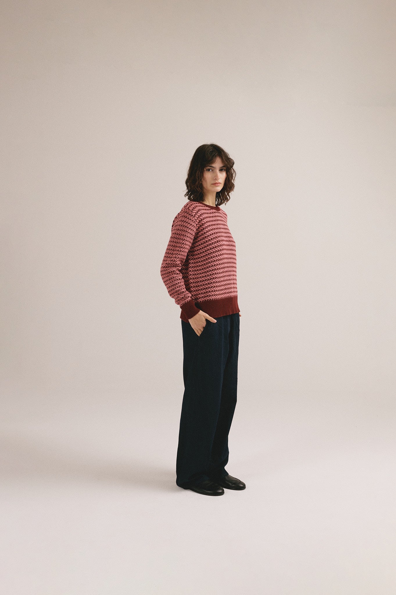 Mujer con jersey de punto rojo con estampado geométrico de IAIOS y pantalón oscuro.