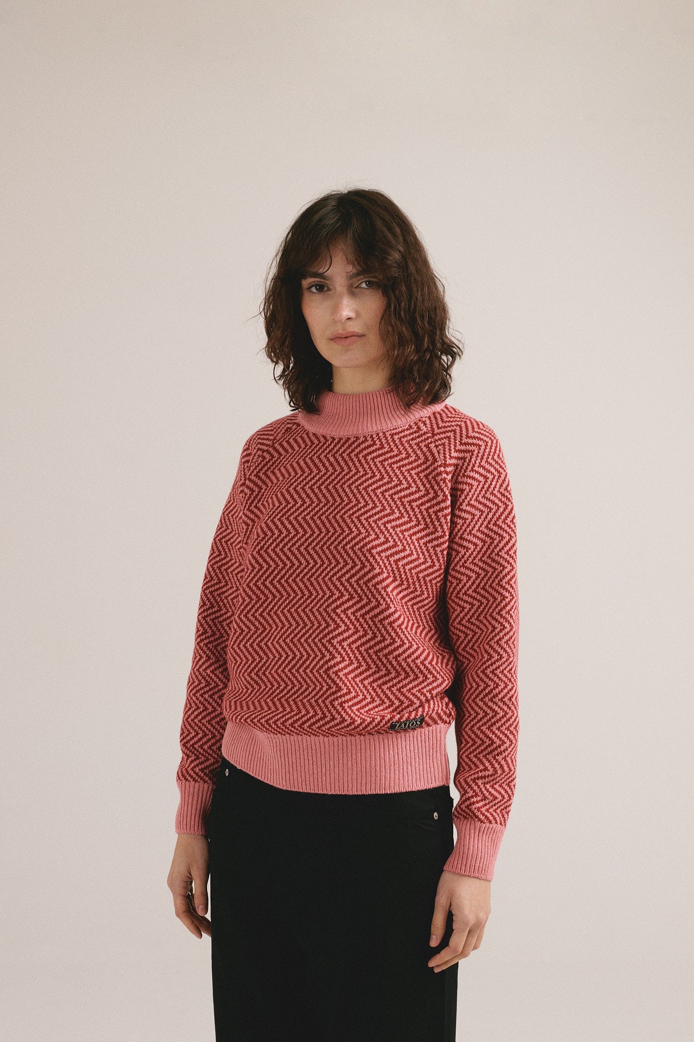 Mujer con jersey de punto rojo con estampado geométrico de IAIOS y pantalón oscuro.