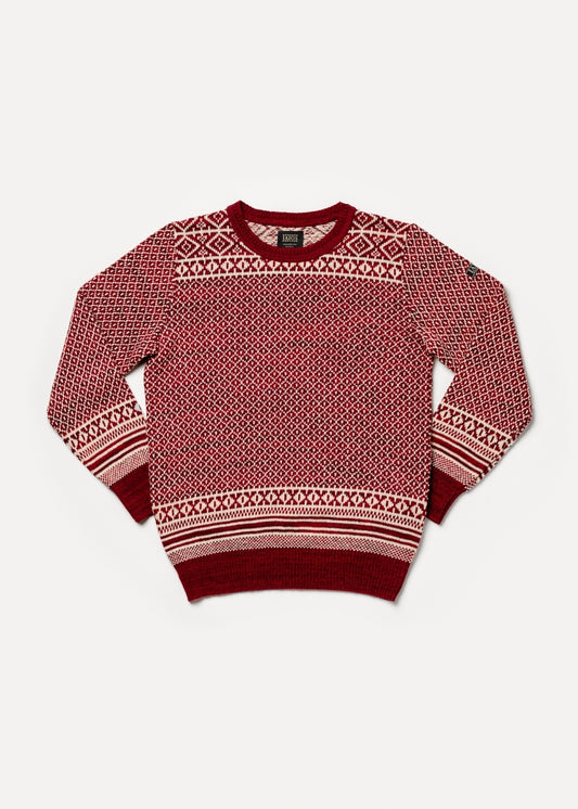 El modelo lleva el jersey unisex IAIOS rojo y blanco con diseño jacquard navideño tipo nórdico, moda sostenible hecha en Catalunya (España) con hilo reciclado, ideal para invierno.