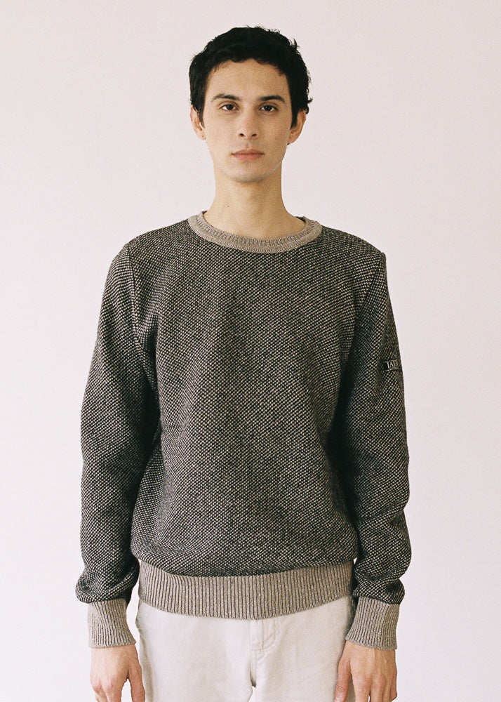 El modelo lleva el jersey IAIOS unisex negro y beige con textura de punto grano de arroz, moda sostenible elaborada en talleres de Catalunya (España) con hilo reciclado.
