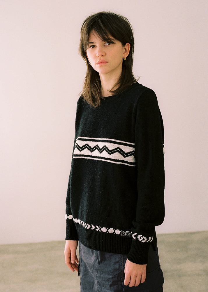 La modelo lleva el jersey de mujer IAIOS negro con motivos en crema, prenda de moda sostenible hecha en Catalunya (España) con hilo reciclado, ideal para invierno.