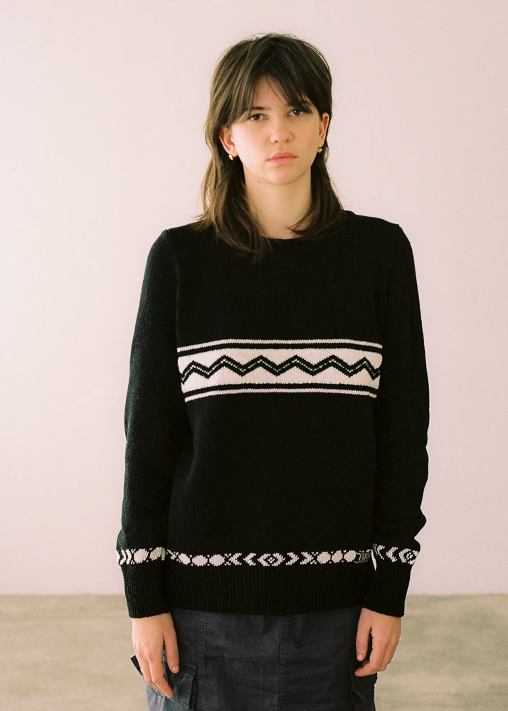 La modelo lleva el jersey IAIOS de mujer negro con elegantes motivos en crema, moda sostenible elaborada en talleres de Catalunya (España) con hilo reciclado.