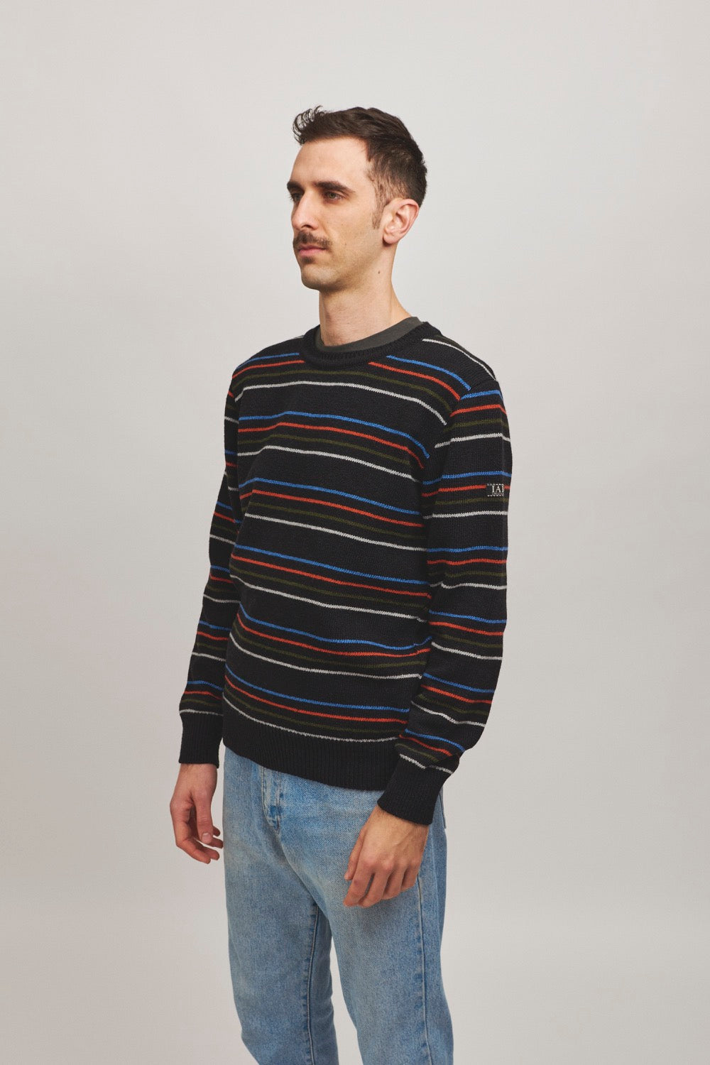 Jersey unisex negro de punto con rayas finas en colores vivos y estilo atemporal, tejido con hilo reciclado en pequeños talleres de Catalunya (España), moda sostenible.