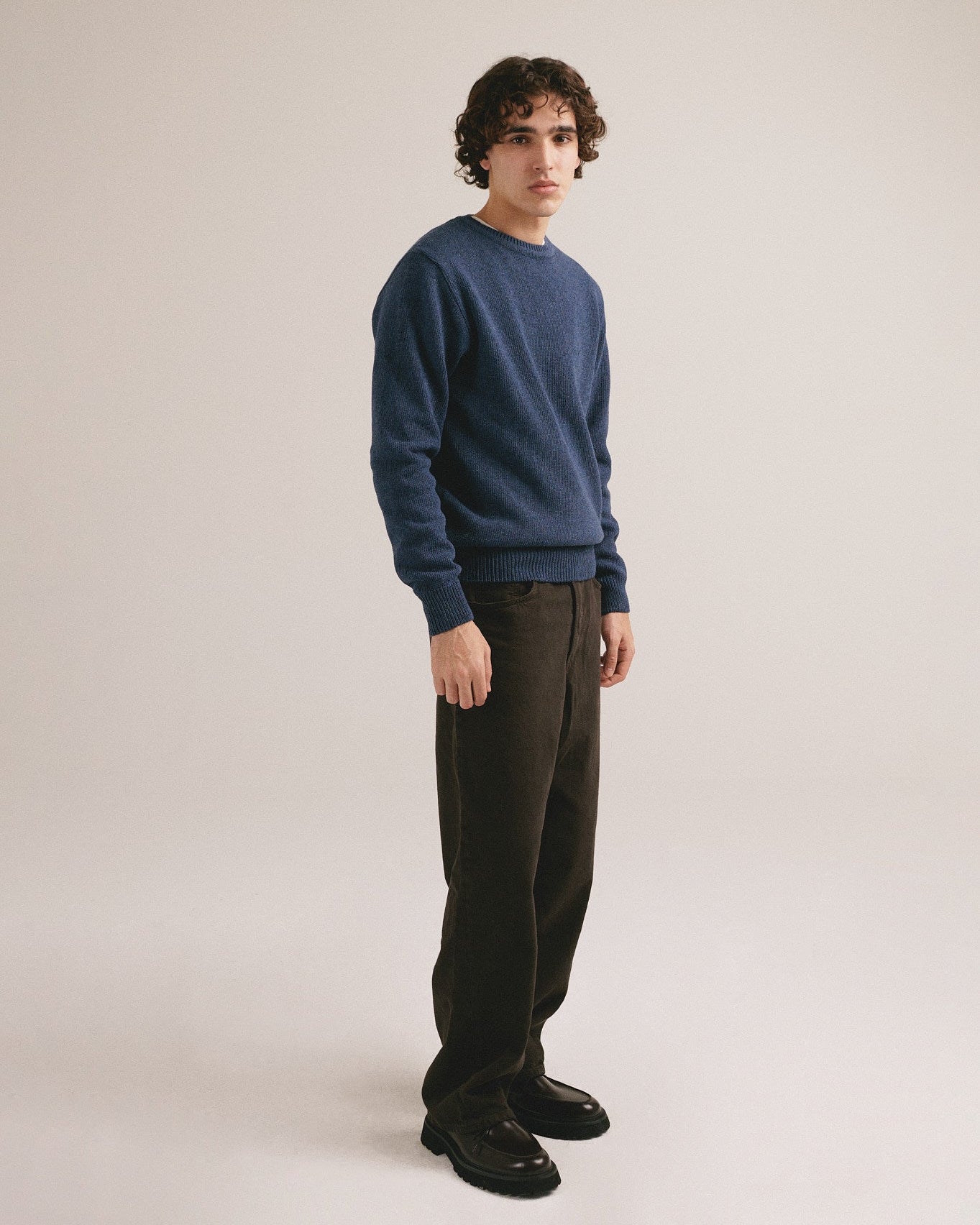 Modelo masculino con suéter de punto azul oliva de manga larga con diseño básico de IAIOS.