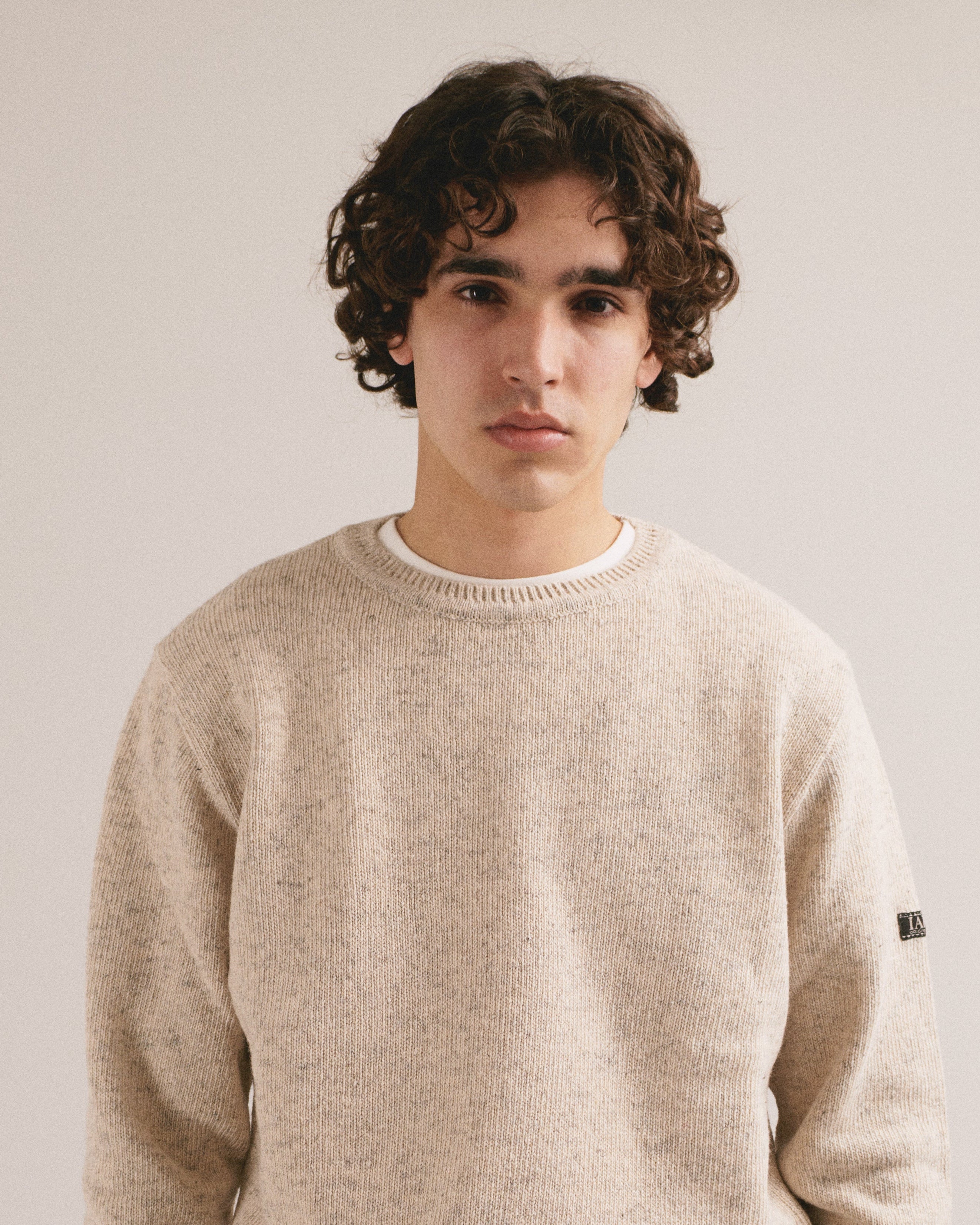Modelo masculino con suéter de punto blanco espigado de manga larga con diseño básico de IAIOS.